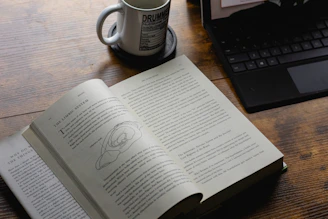 An open book with a coffee mug and laptop.