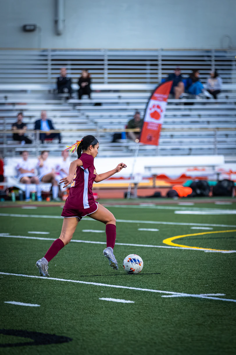 A young woman playing soccer on a field.