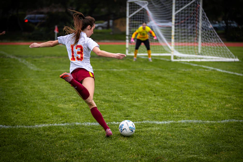 A female soccer player kicks the ball towards the goal.