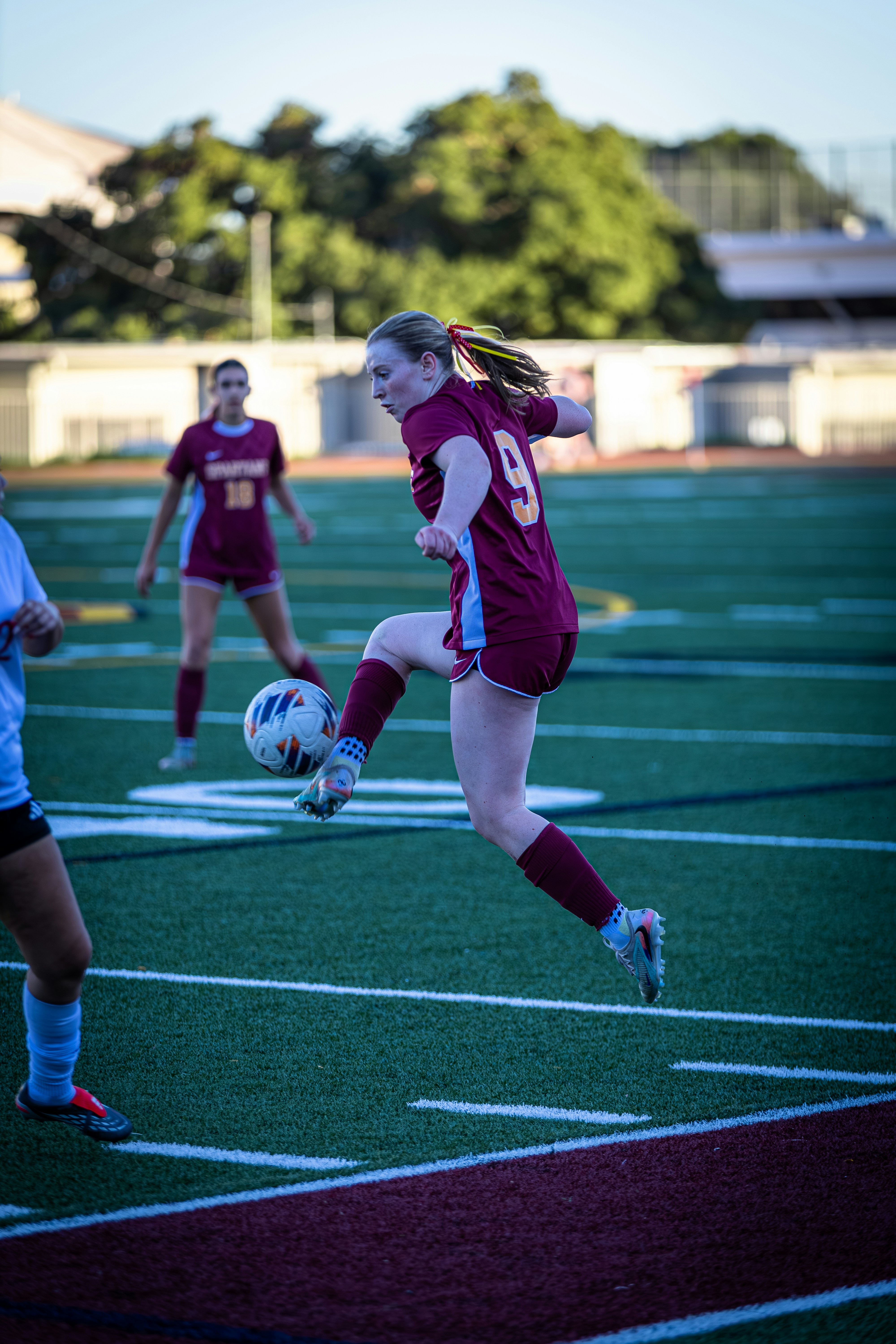 A female soccer player kicks the ball during a game.