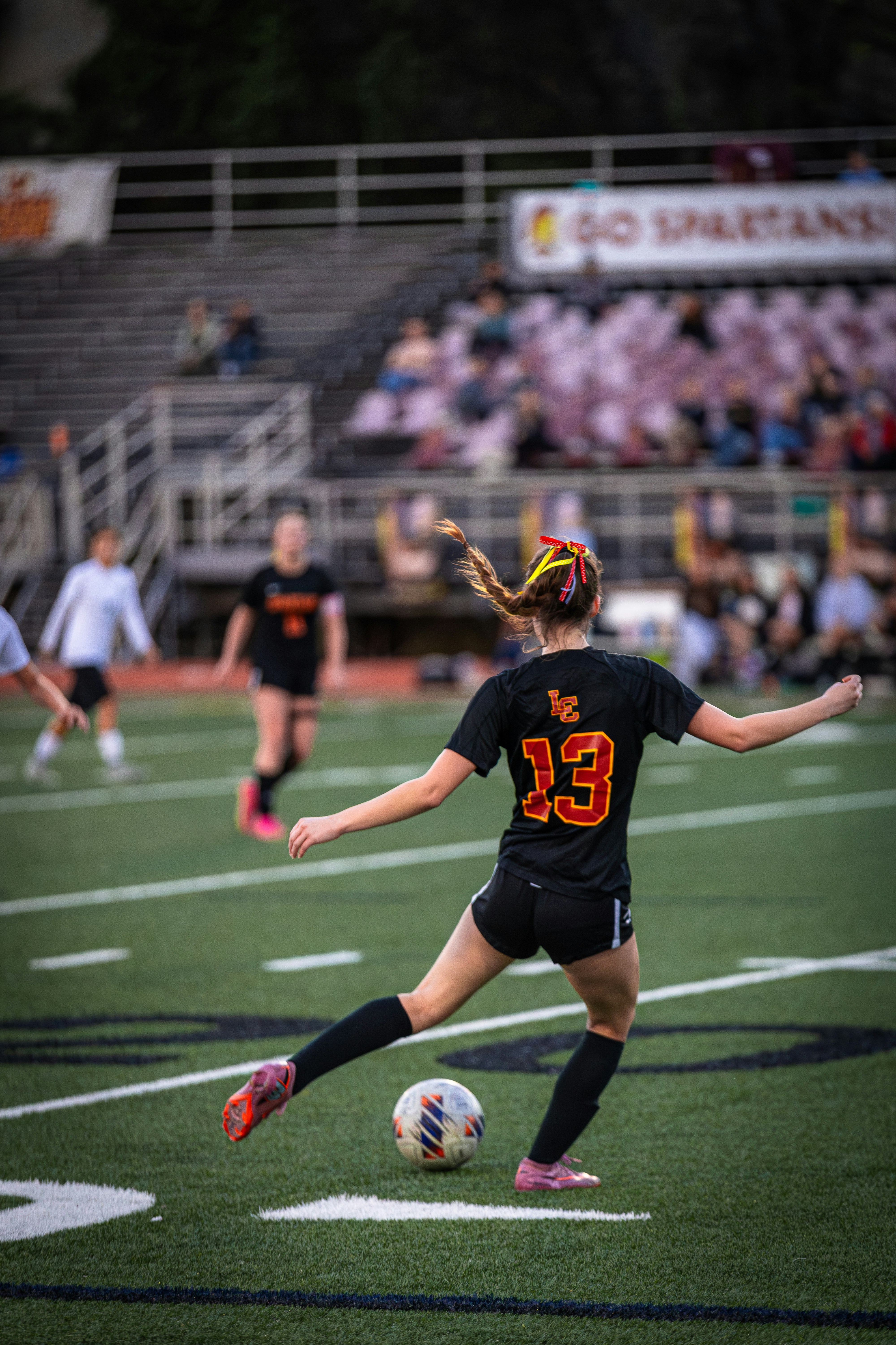 A girl kicks a soccer ball on a field.