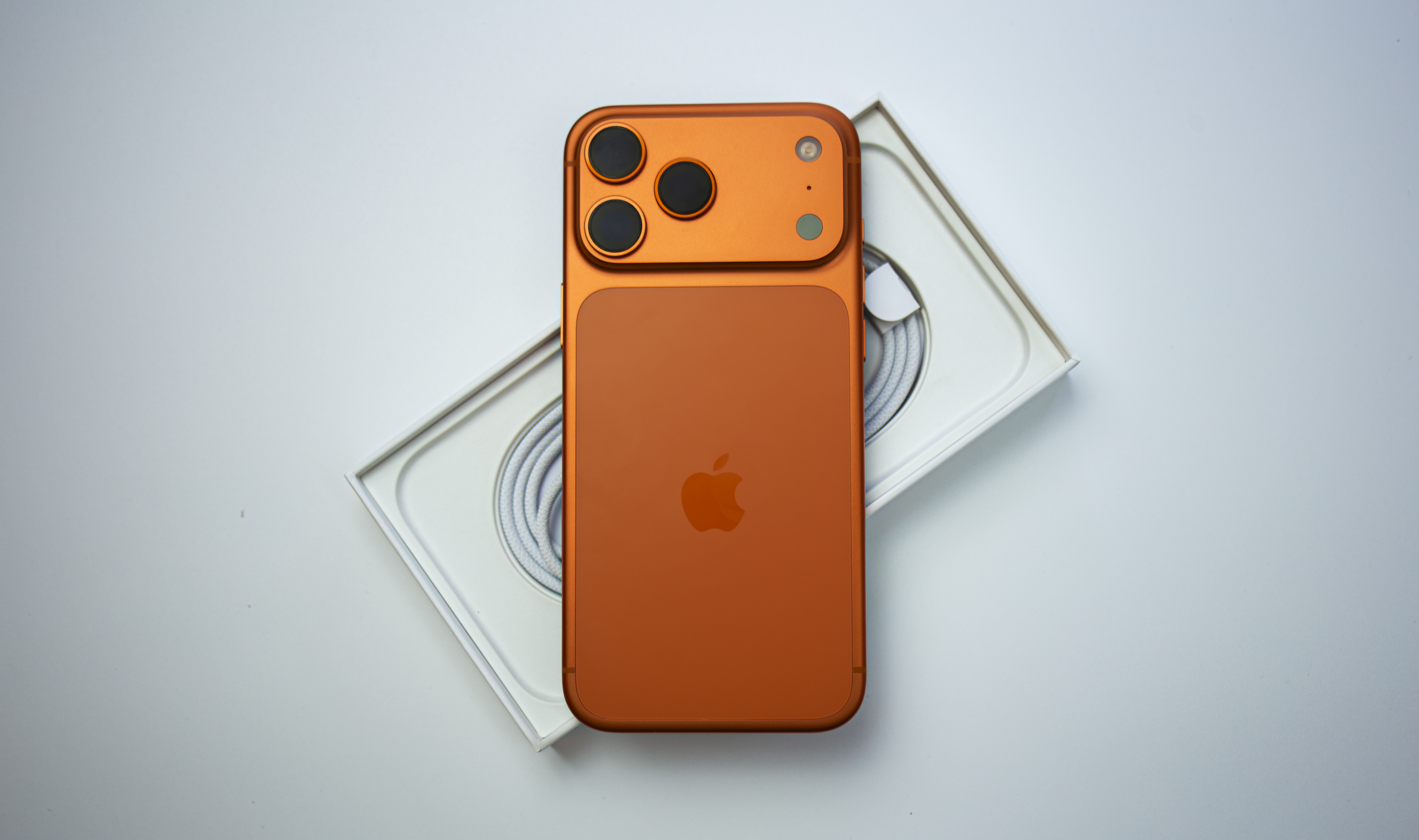 Orange smartphone with apple logo and camera lenses.