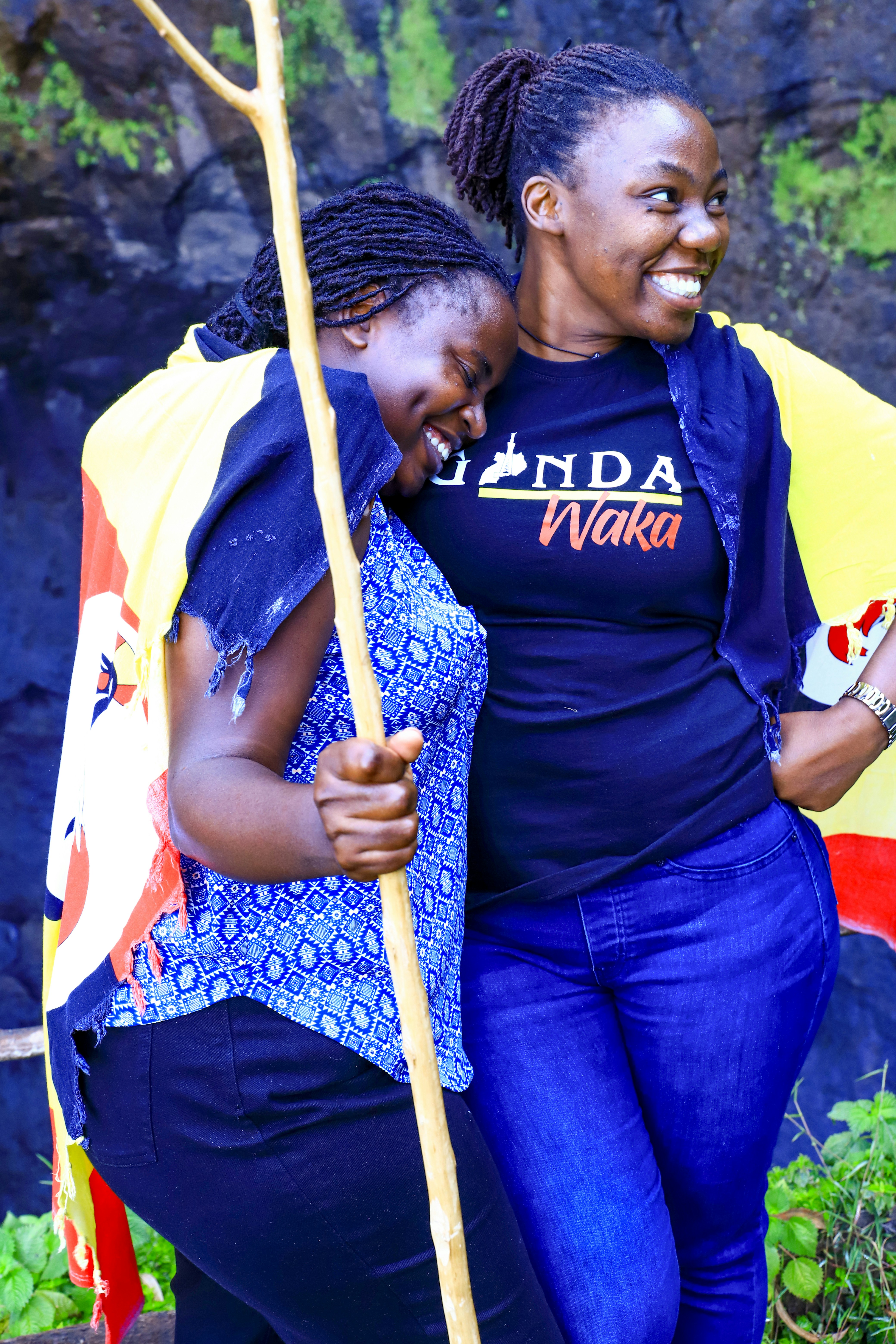 Two smiling women embracing, draped in a colorful cloth.