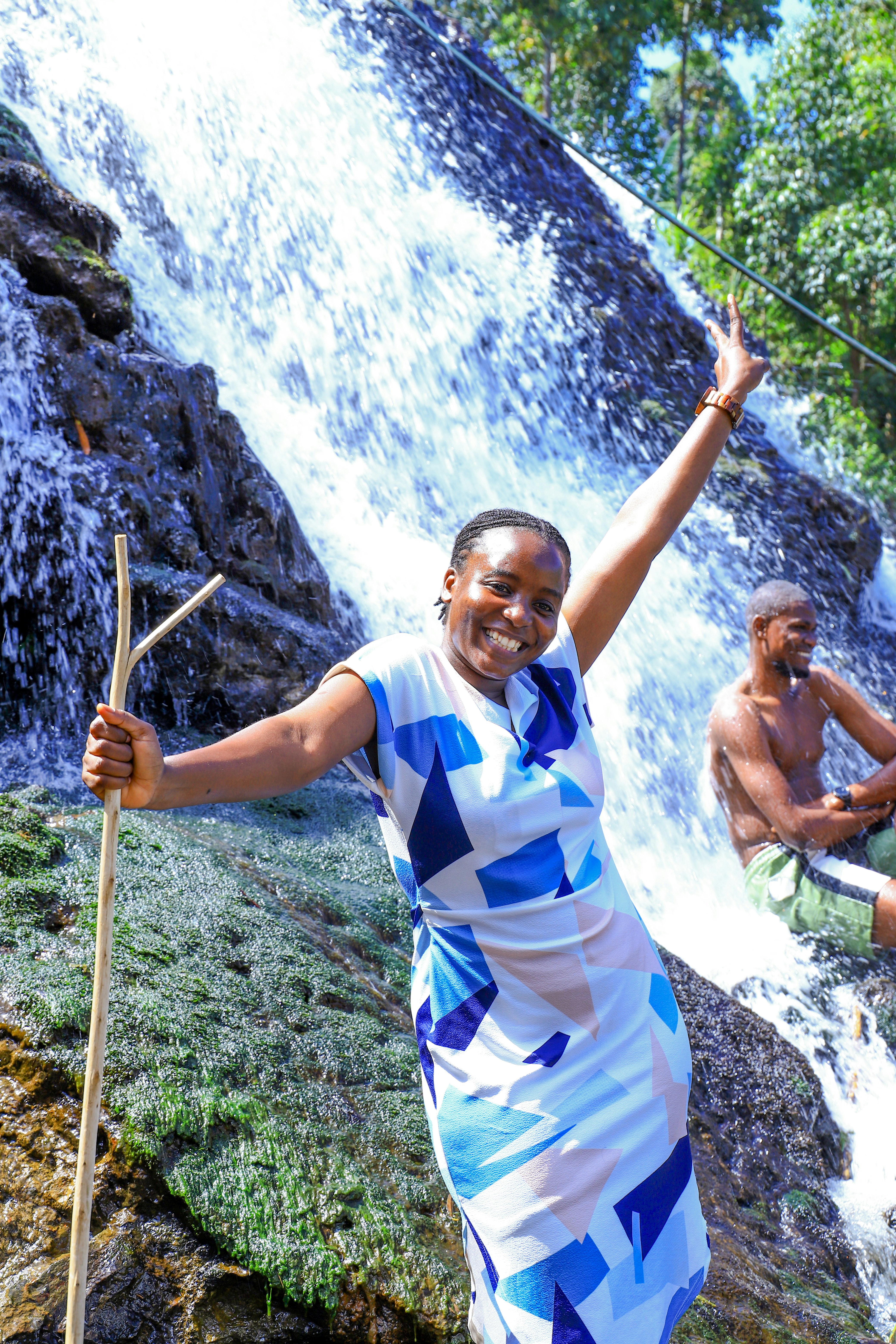 Woman posing with stick near a waterfall
