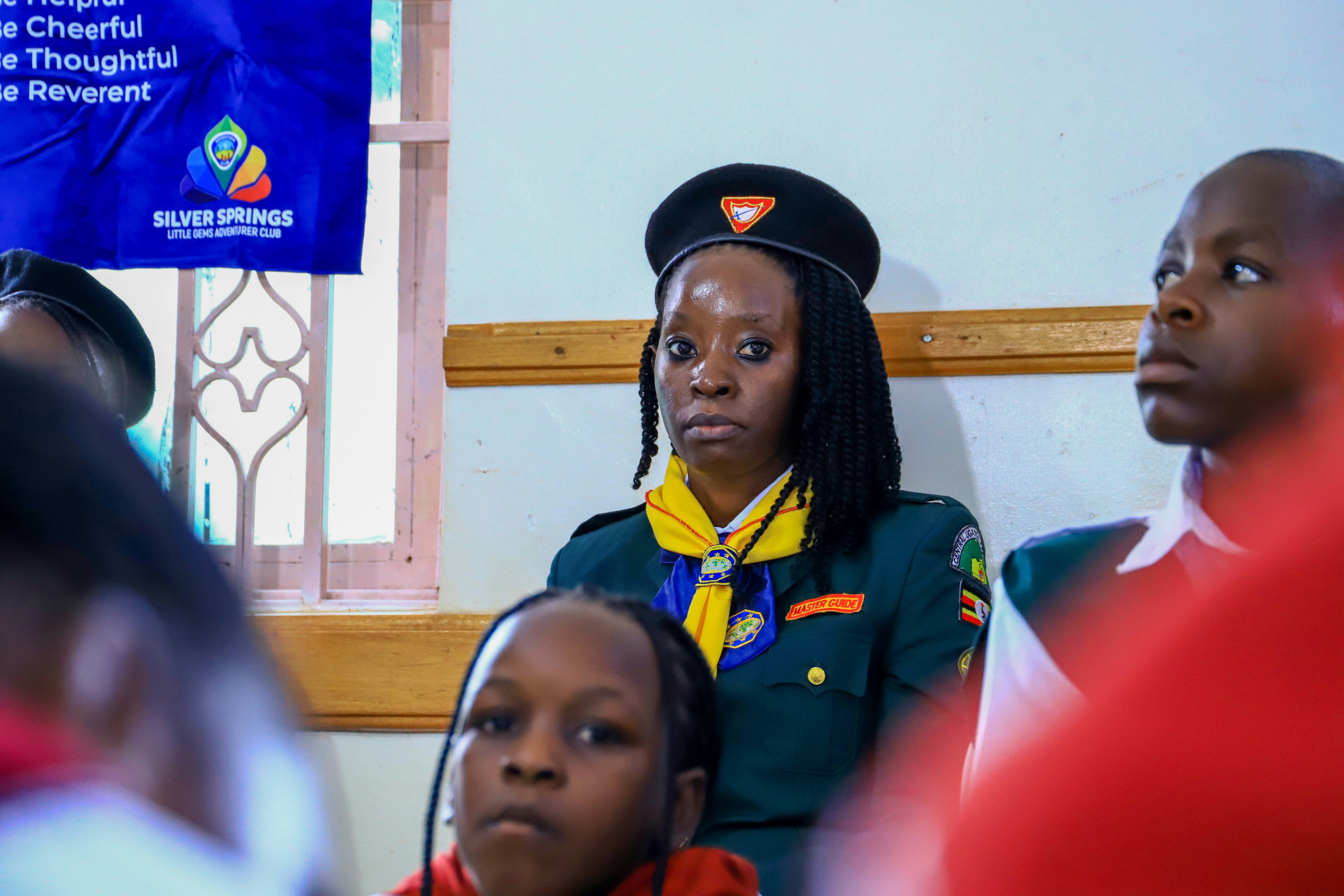 A woman in a scout uniform looks forward attentively