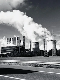 Industrial power plant with smoke billowing from stacks.