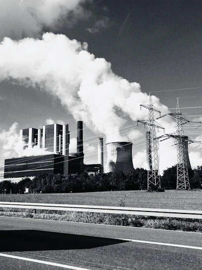 Industrial power plant with smoke billowing from stacks.