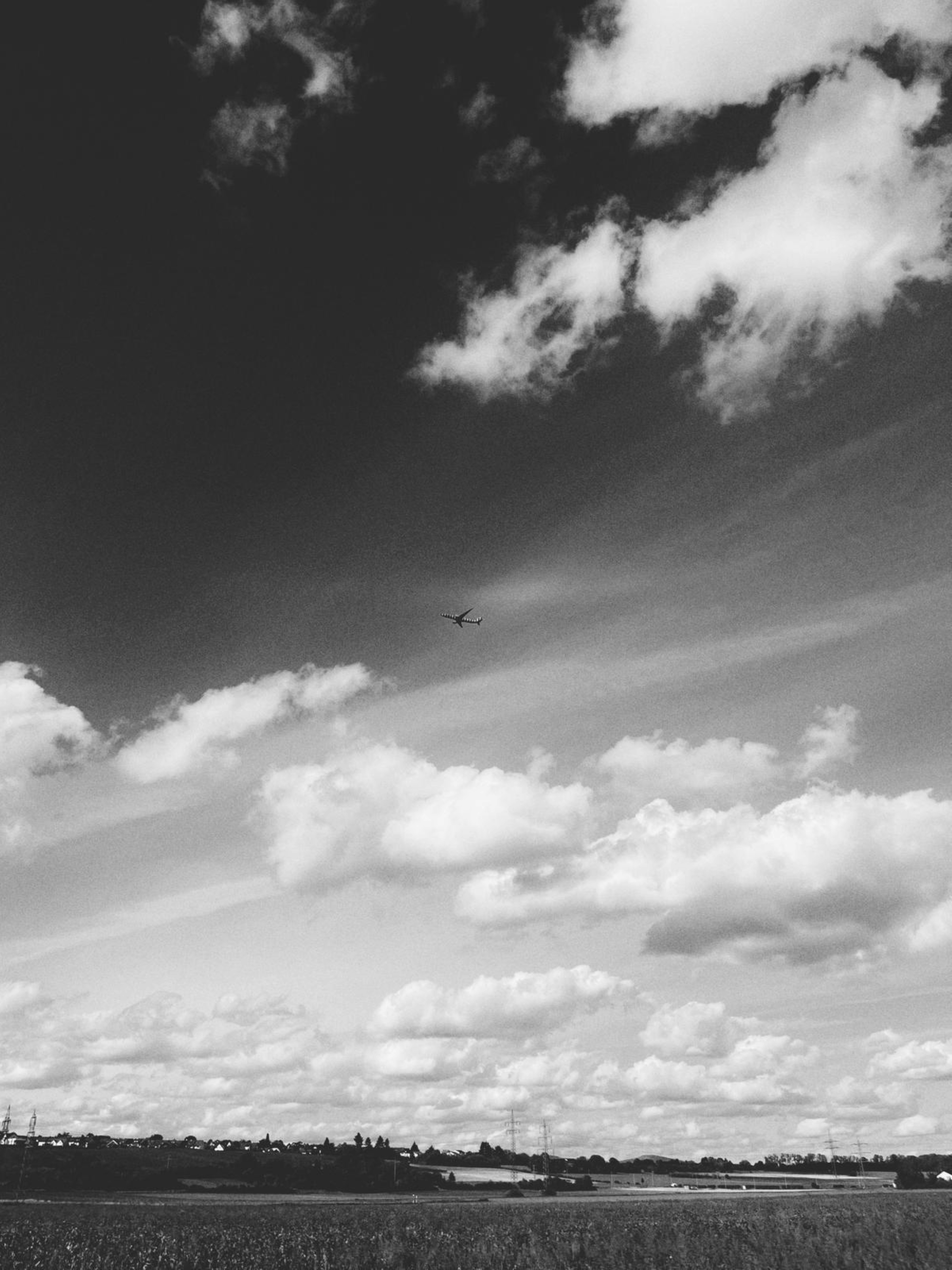A lone airplane flies through a cloudy sky.