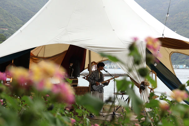 Musicians play under a large tent near water.