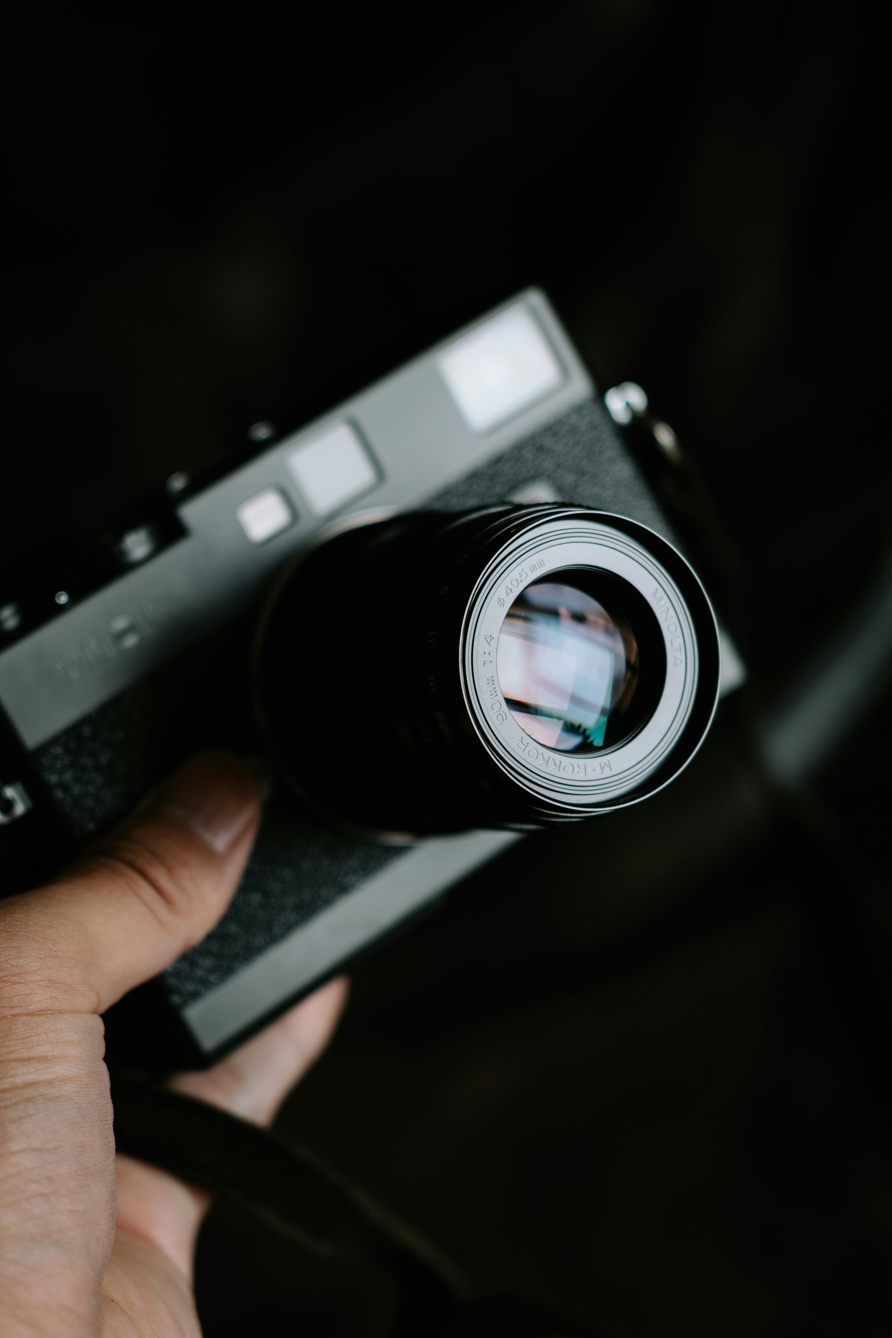 A hand holds a vintage camera with a large lens.