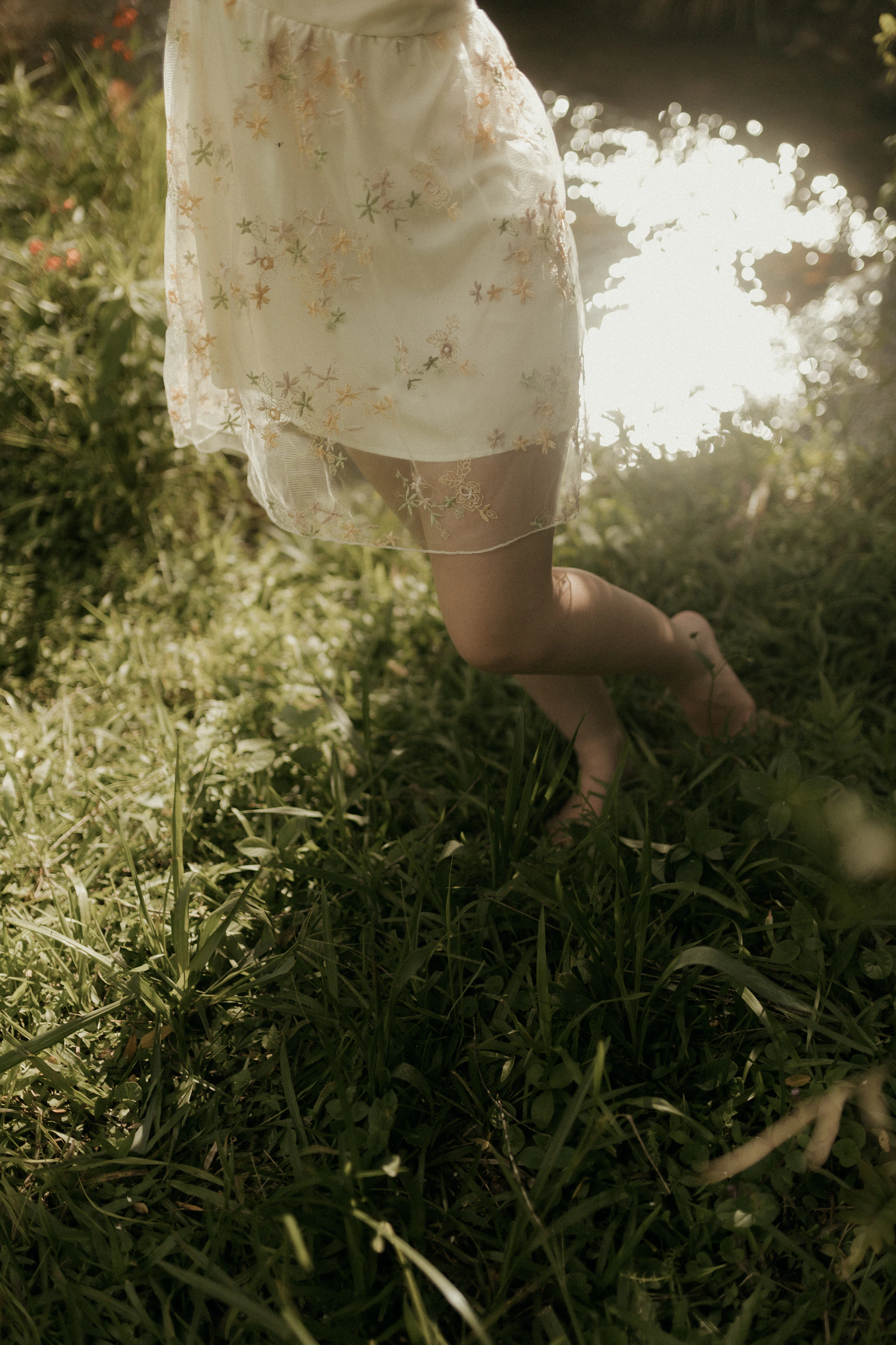 Woman in a floral dress standing in tall grass.