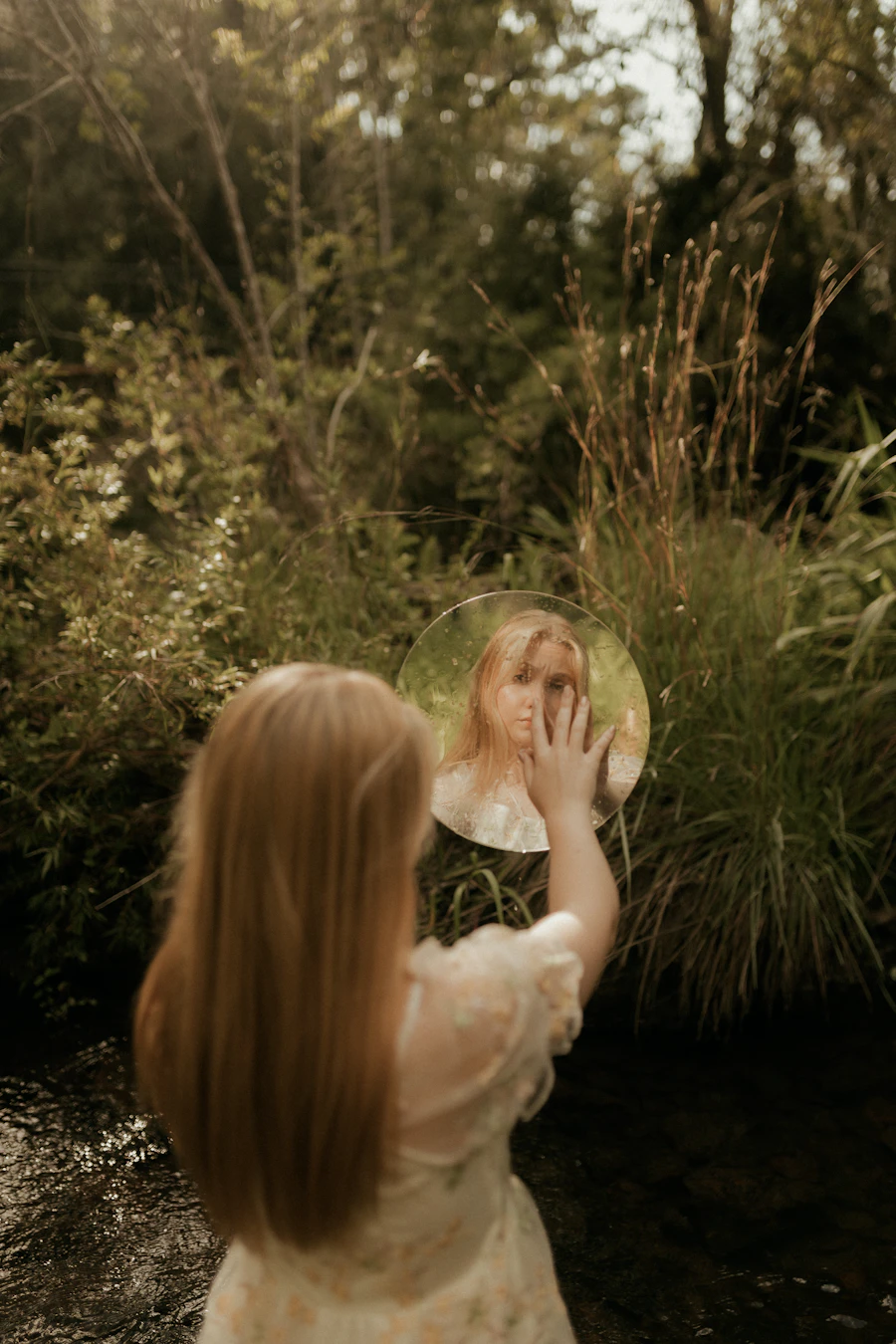 A young woman looking at her own reflection outdoors, a moment of self-examination