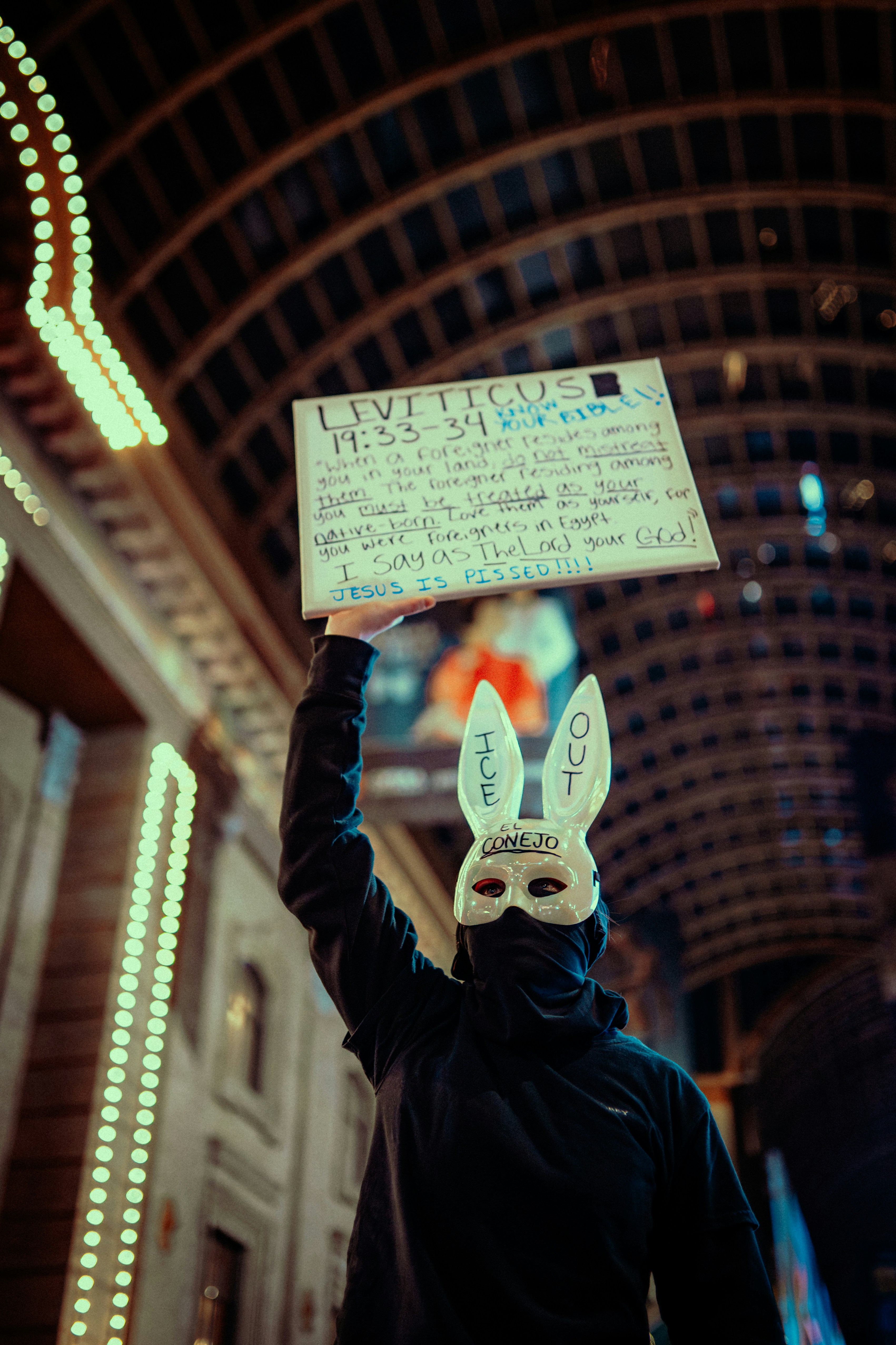 Personne masquée tient un panneau avec un texte