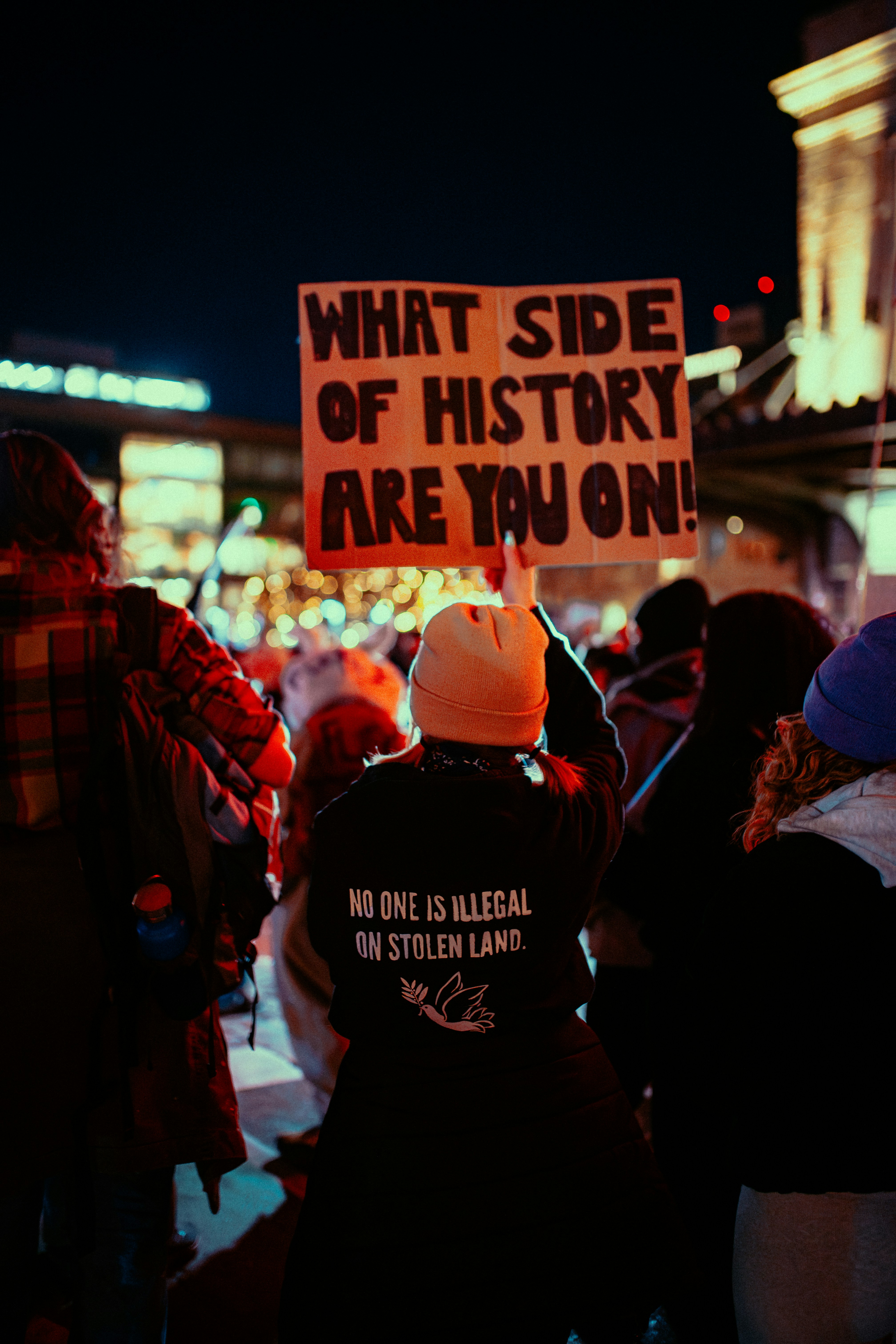 Des manifestants tiennent des pancartes lors d’un rassemblement nocturne.