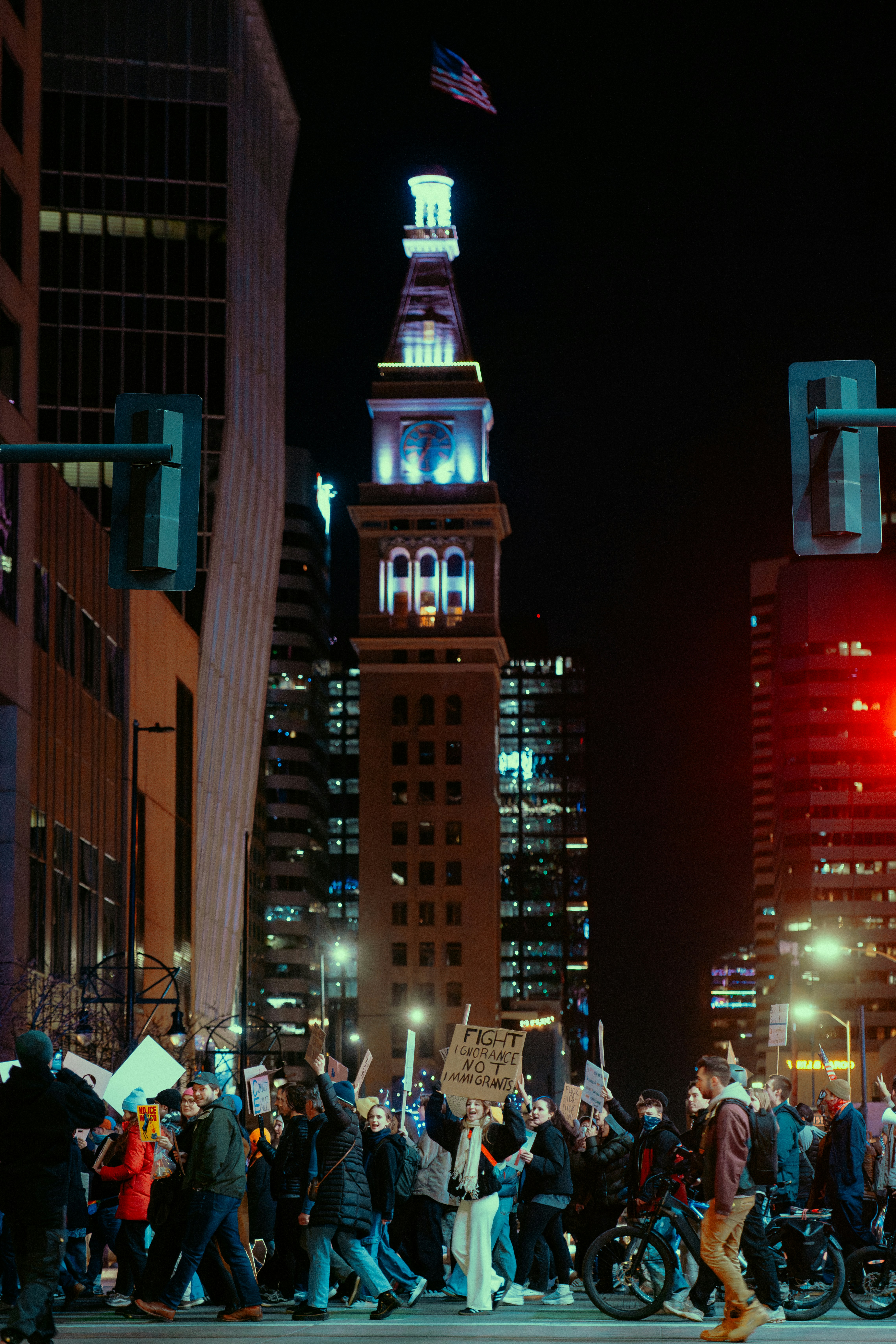 Folla protesta in una città di notte con edifici alti.