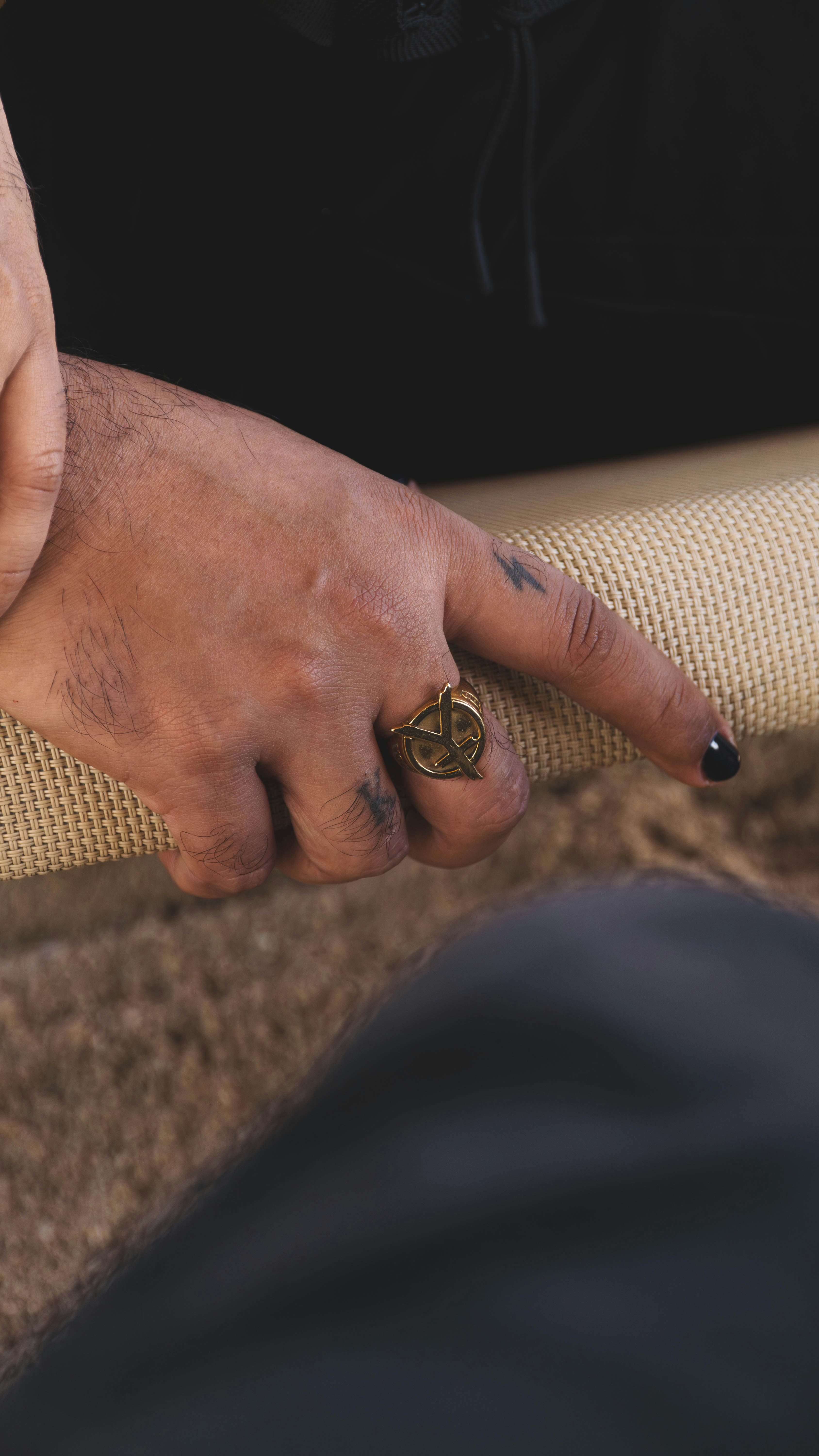 Close-up of a hand wearing a ring with tattoos.