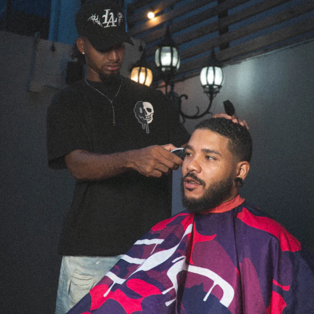 A barber cutting a client's hair with electric clippers