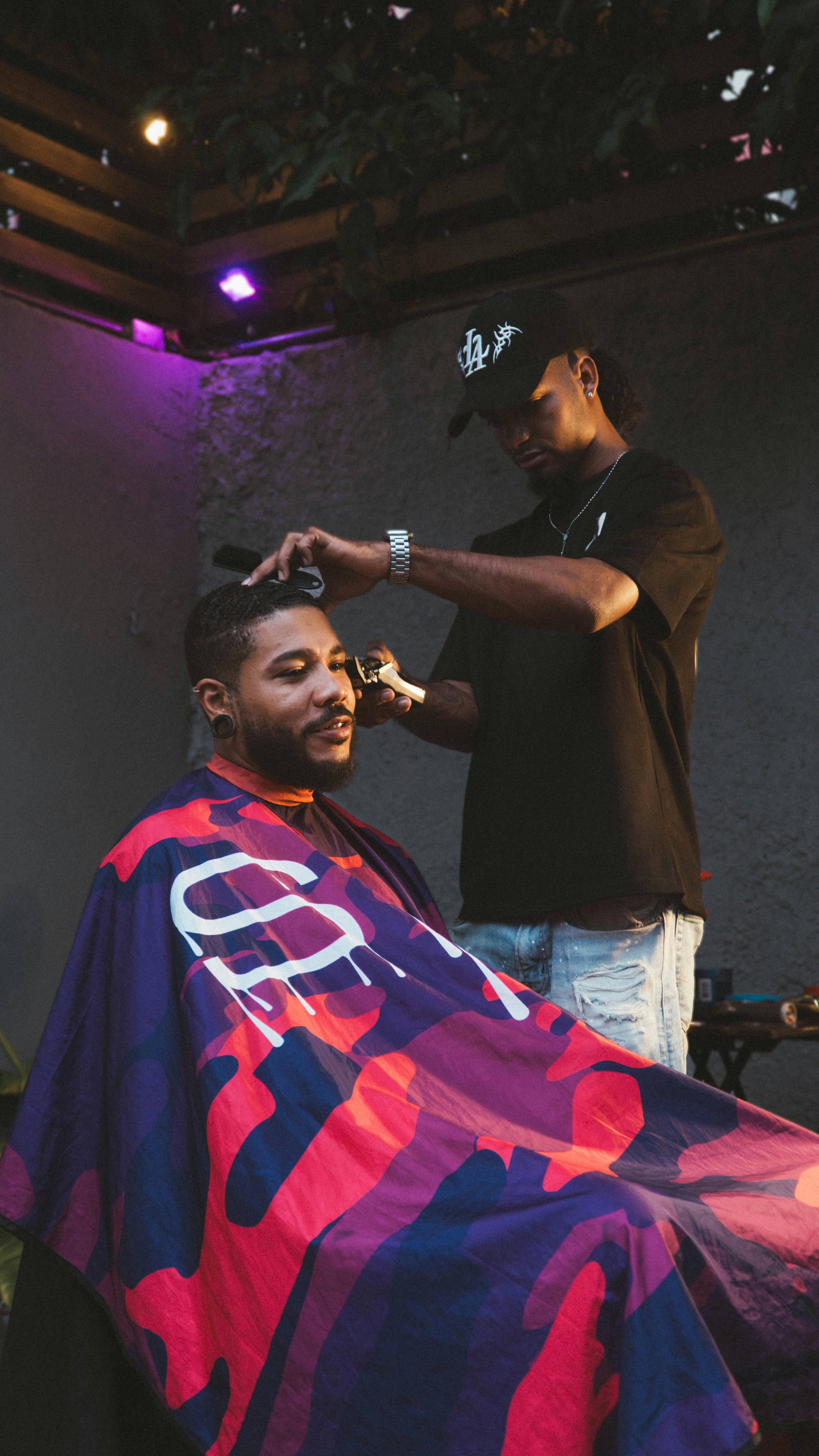 Barber cutting hair of a man with colorful cape.