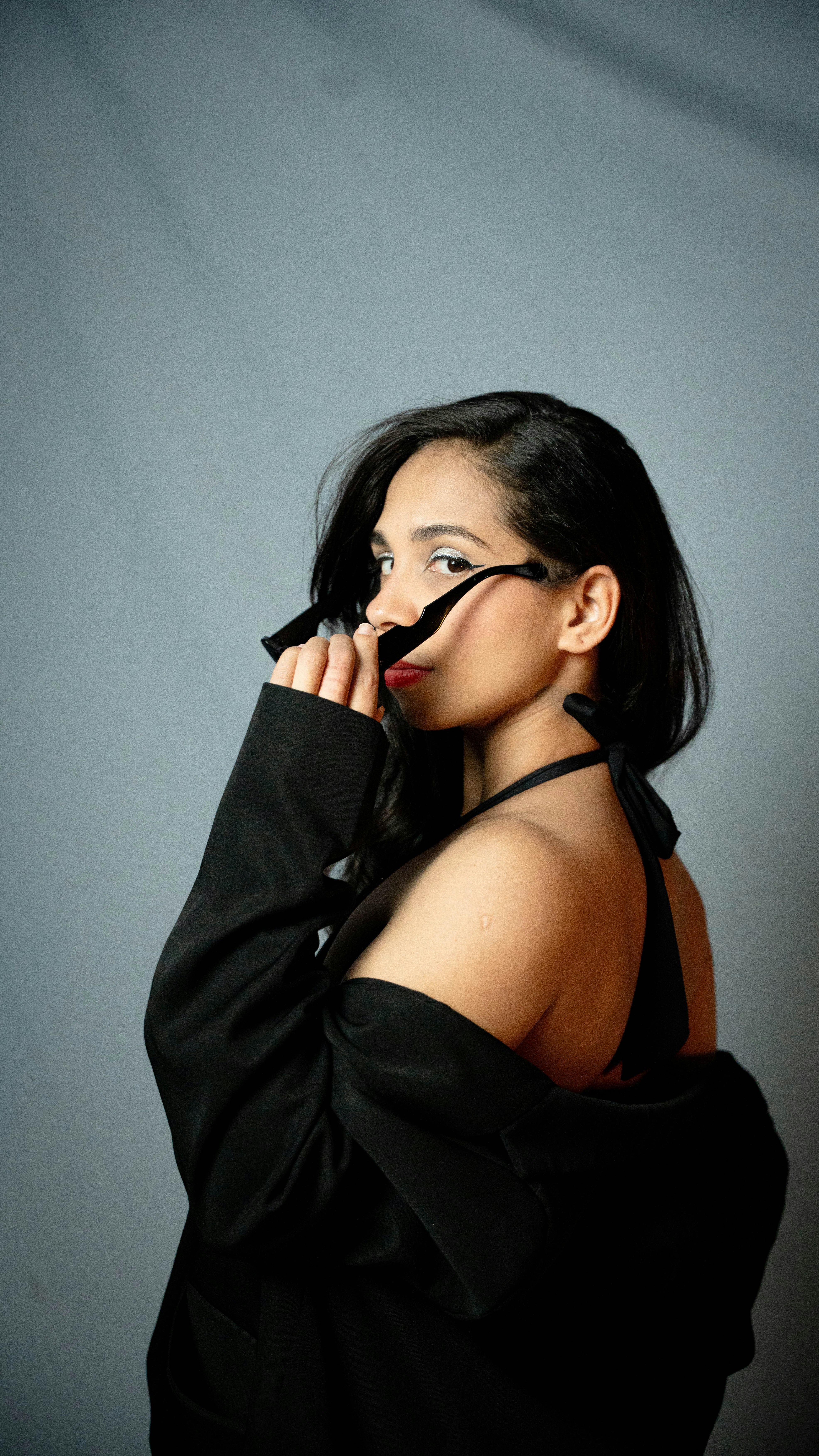 Woman in black blazer adjusts sunglasses over her face