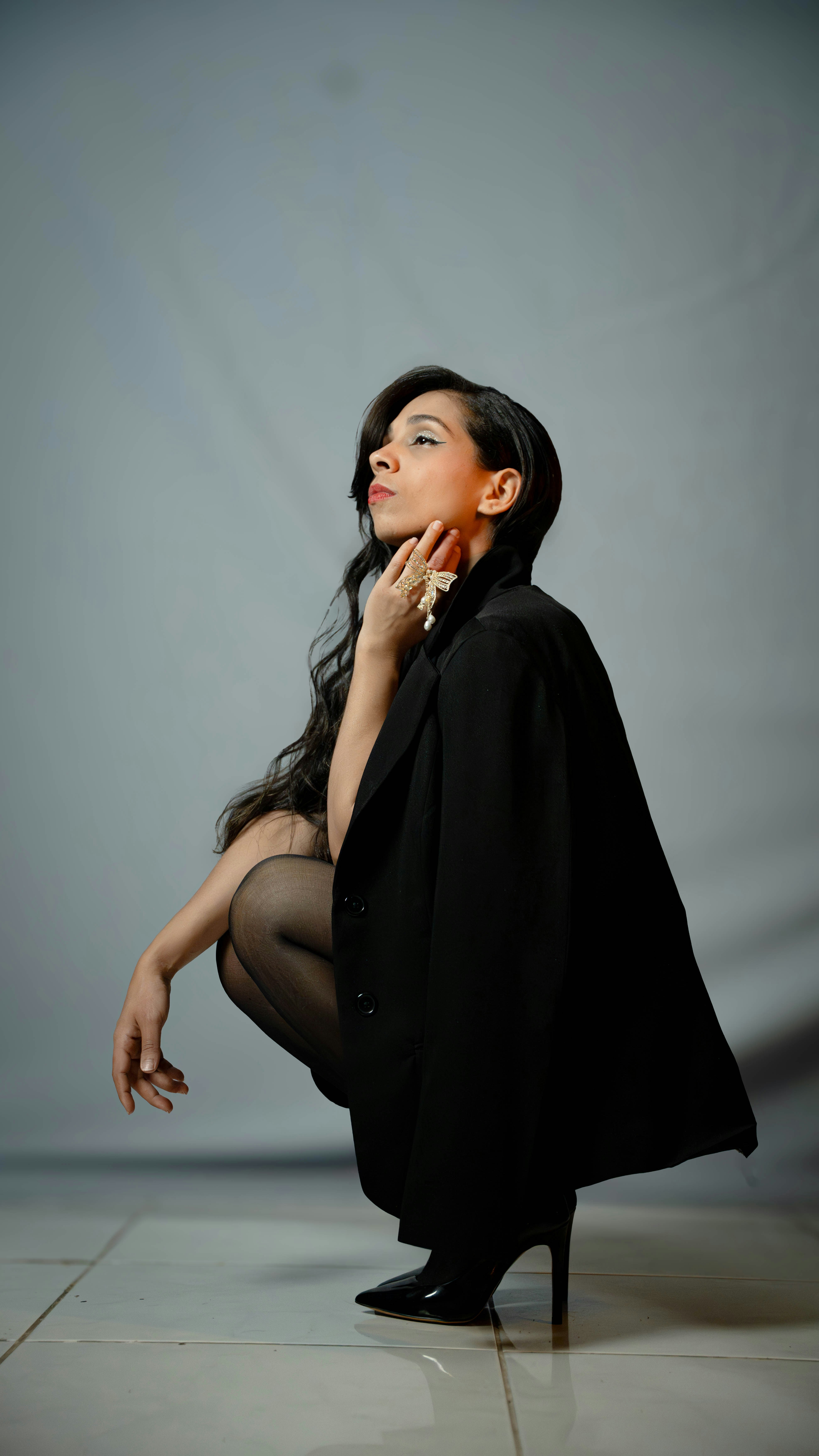 Woman in black blazer and heels crouching