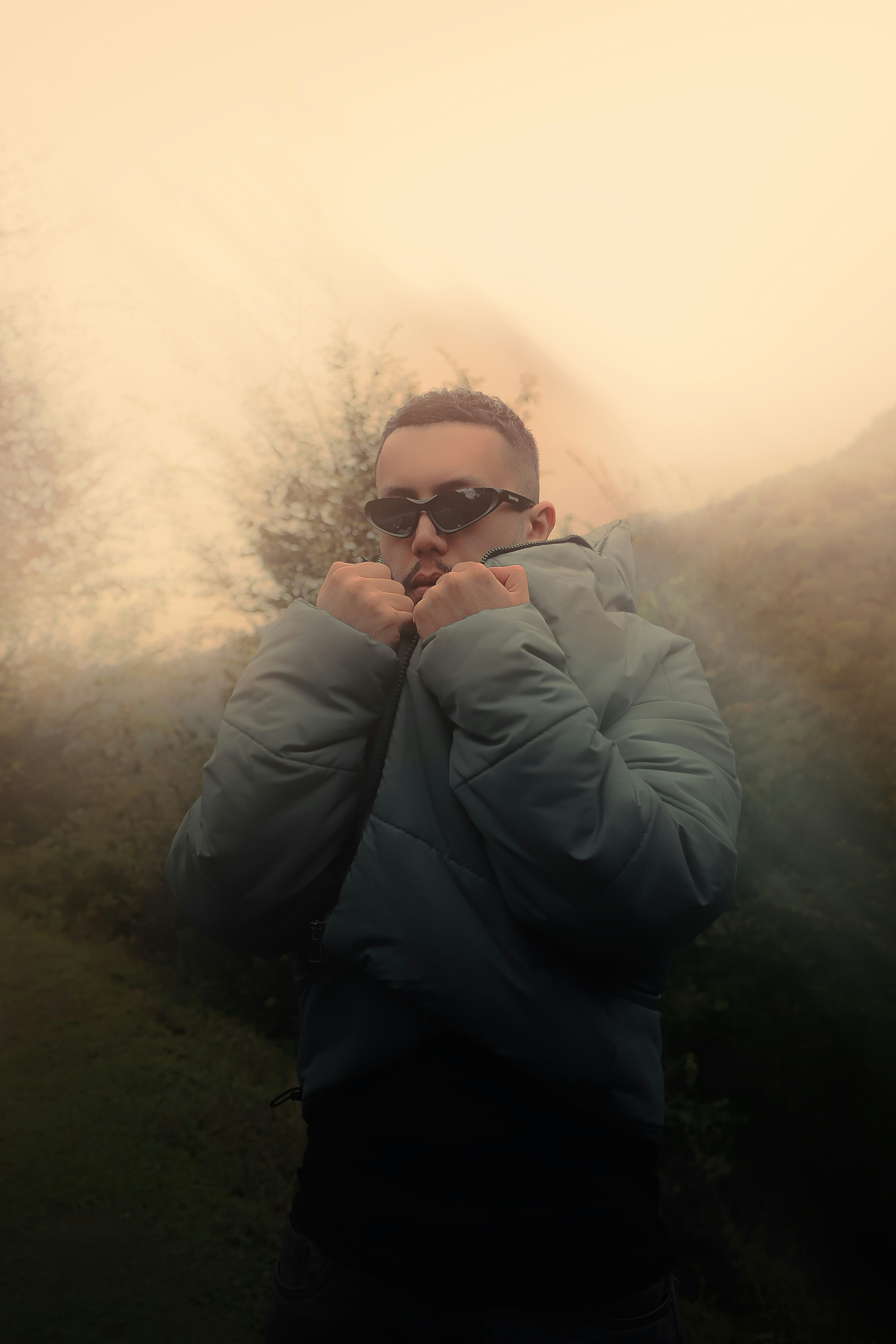 Man in puffer jacket and sunglasses in foggy landscape
