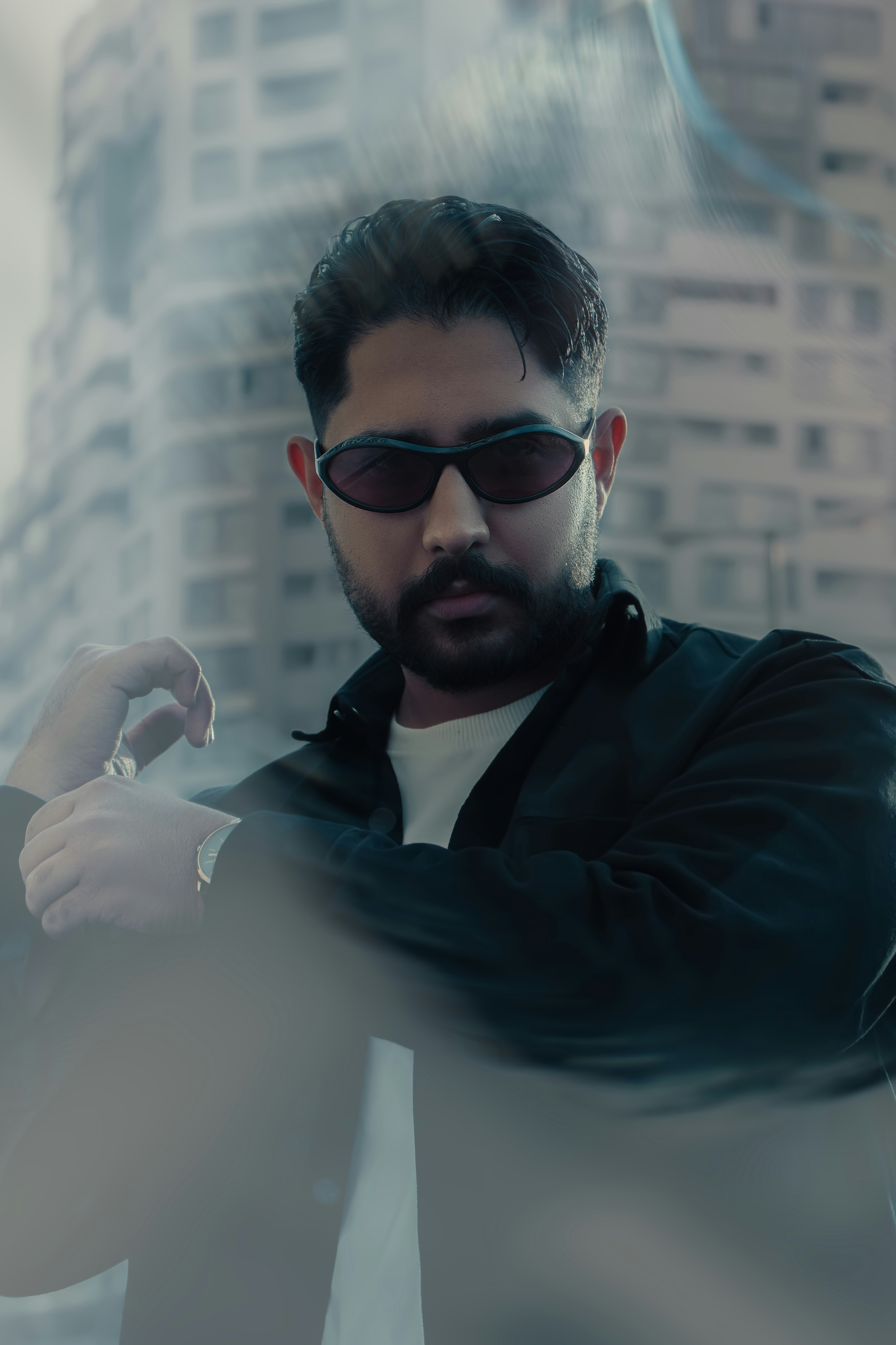Man wearing sunglasses with a blurred cityscape background