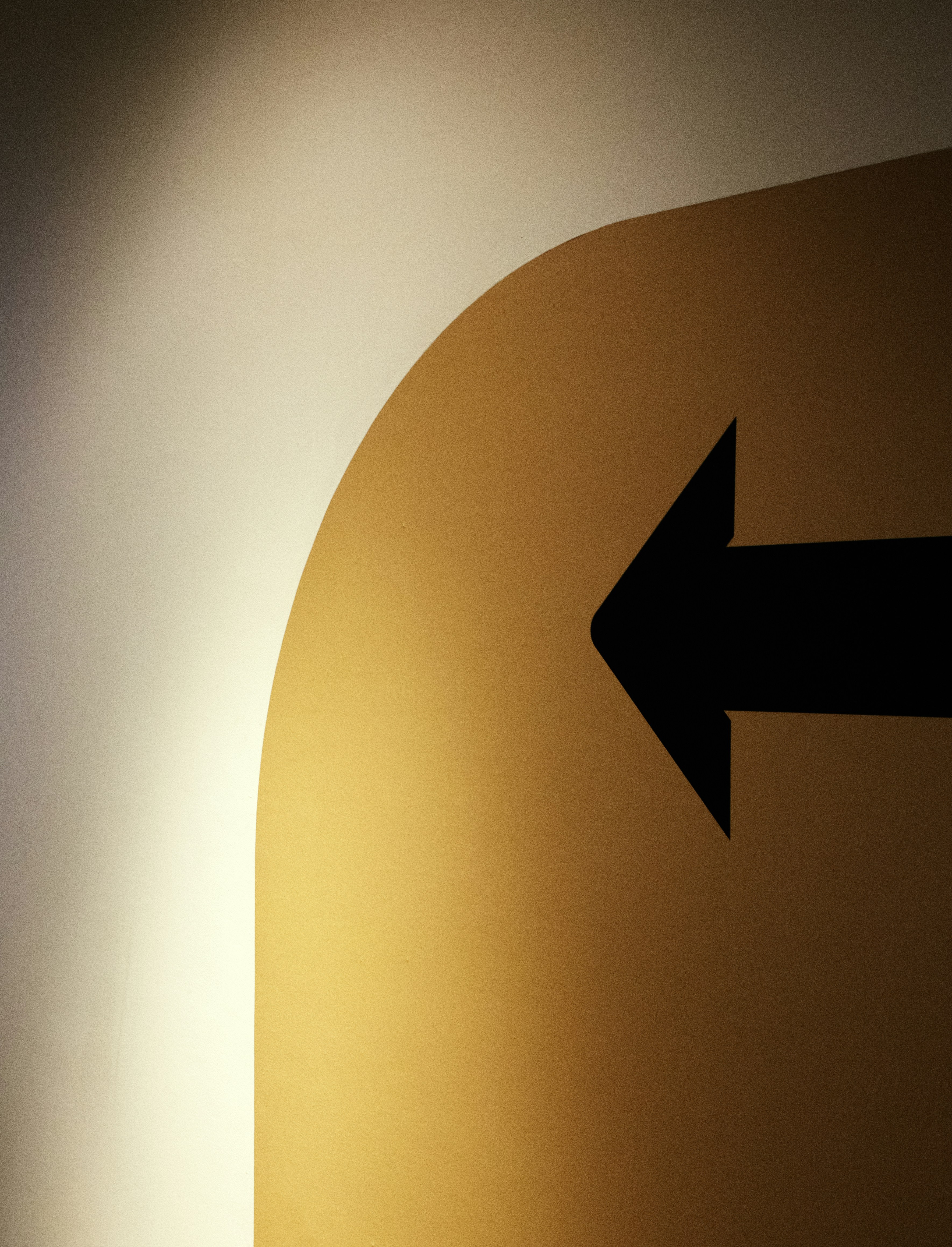 Schwarzer Pfeil, der nach links auf eine gelbe Oberfläche zeigt.