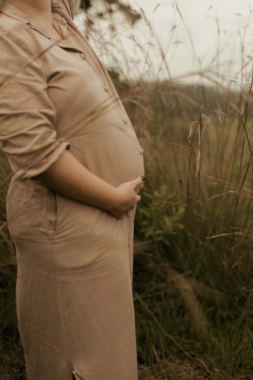 Pregnant woman holding her belly in a field