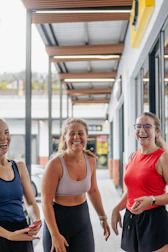 Three women laughing outdoors in activewear