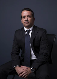 Man in a suit sitting with hands clasped