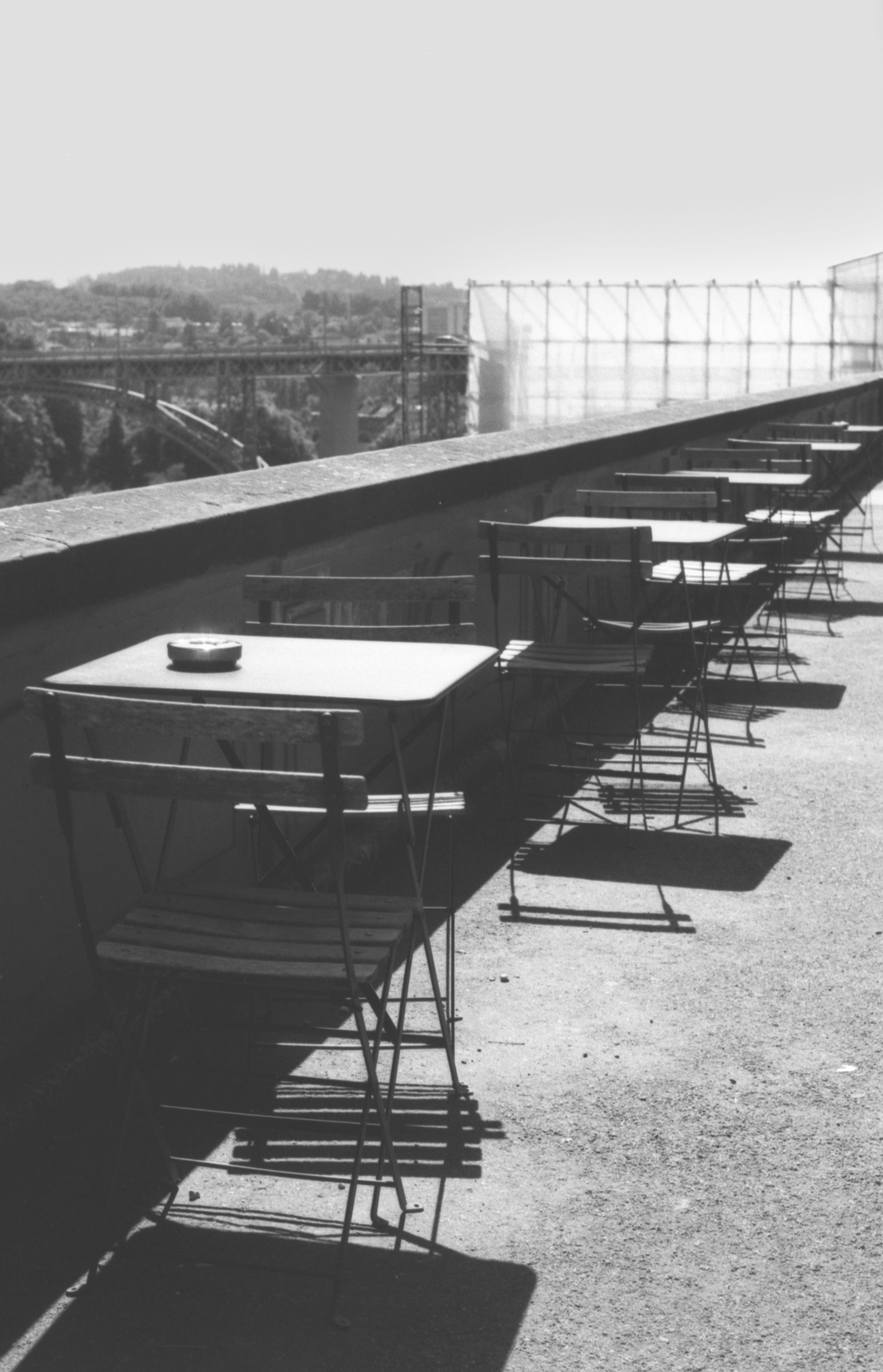 Empty outdoor cafe tables and chairs with bridge background
