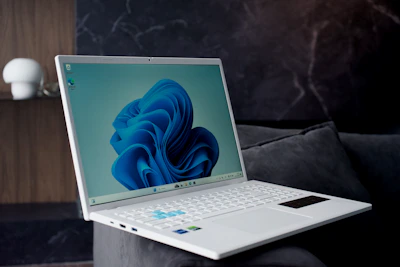 A modern white laptop with a blue abstract wallpaper.