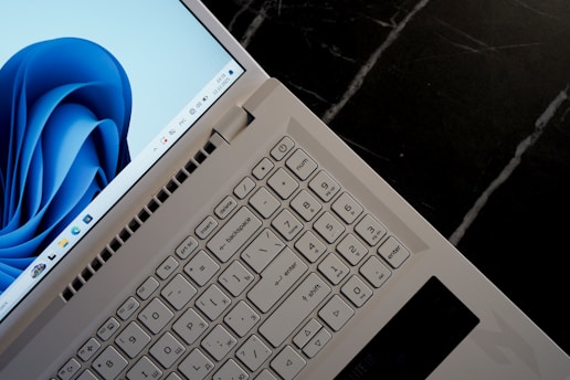 A white laptop with a blue abstract wallpaper open.
