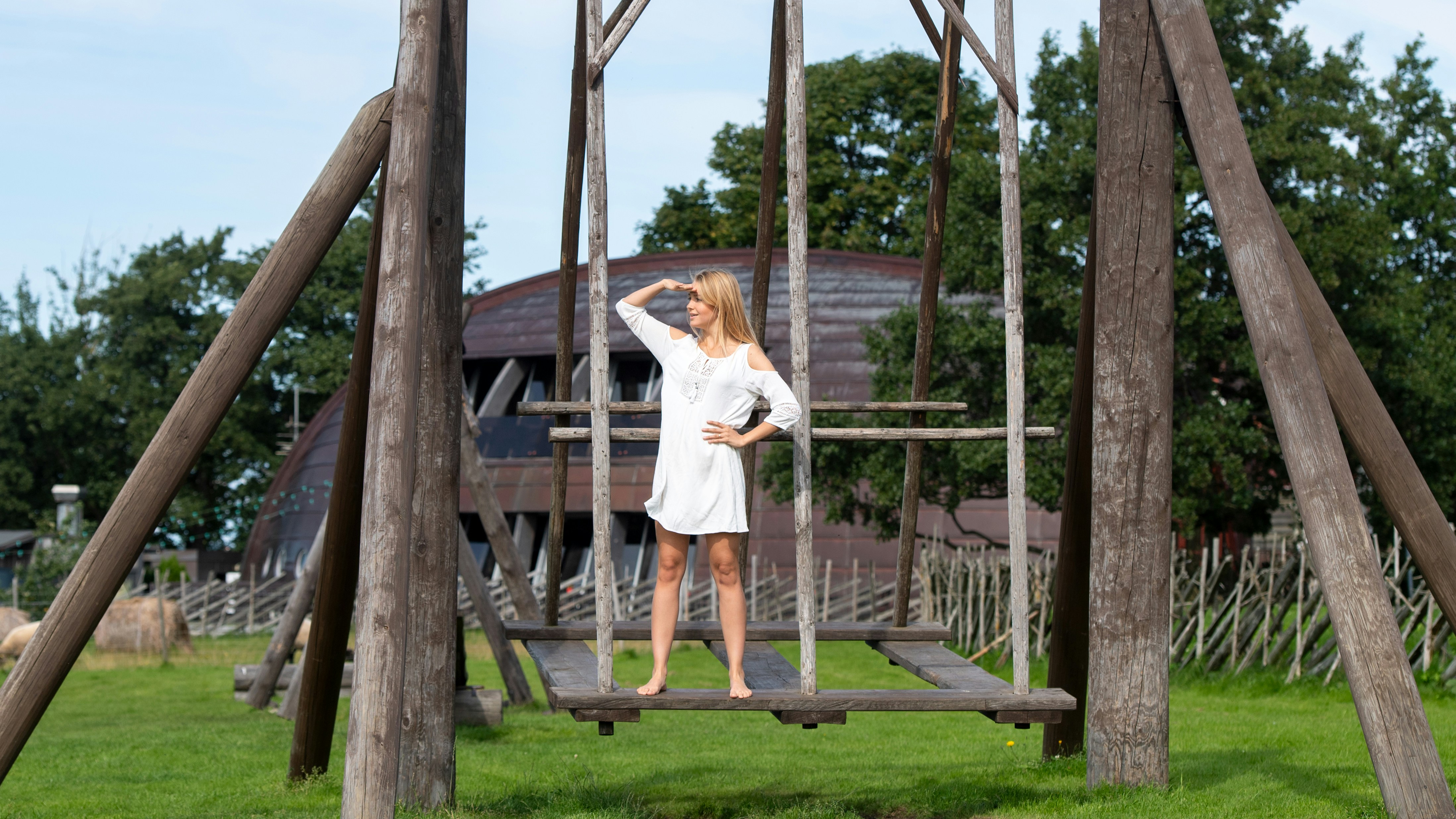 Woman in white dress on wooden swing set