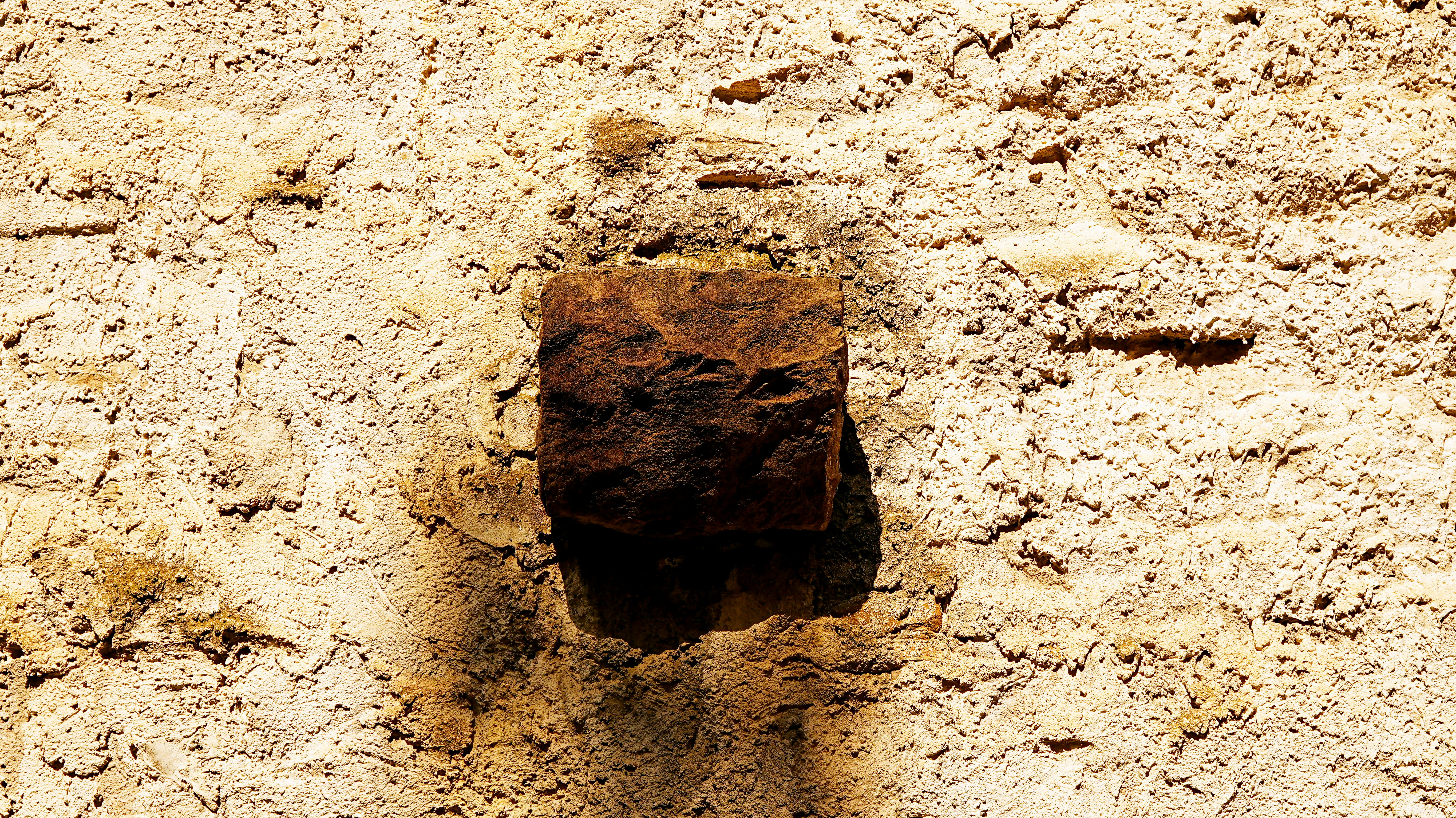 Eine rostige Metallhalterung an einer strukturierten Wand.