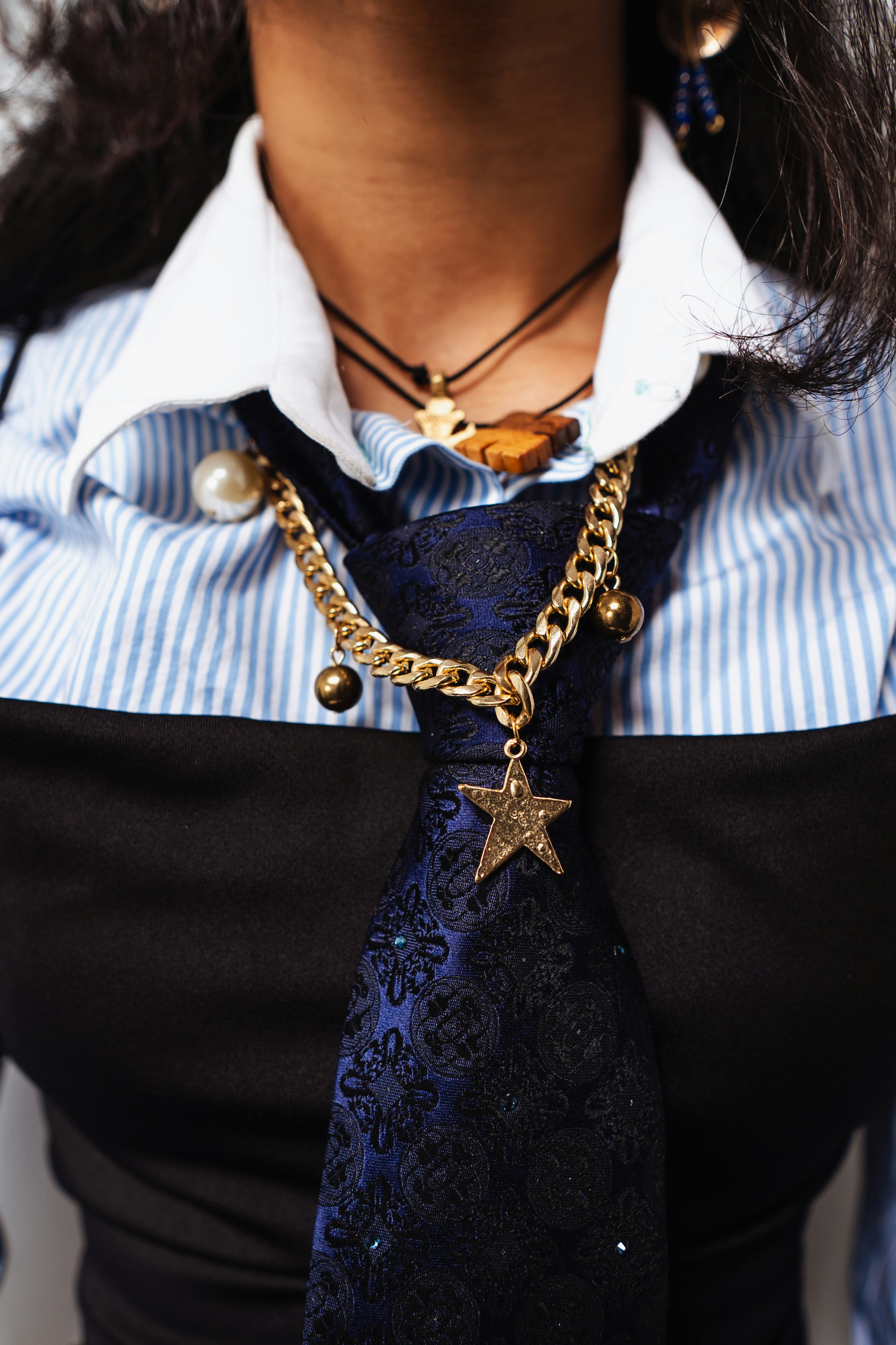 Mujer con camisa de rayas y corbata con joyas.