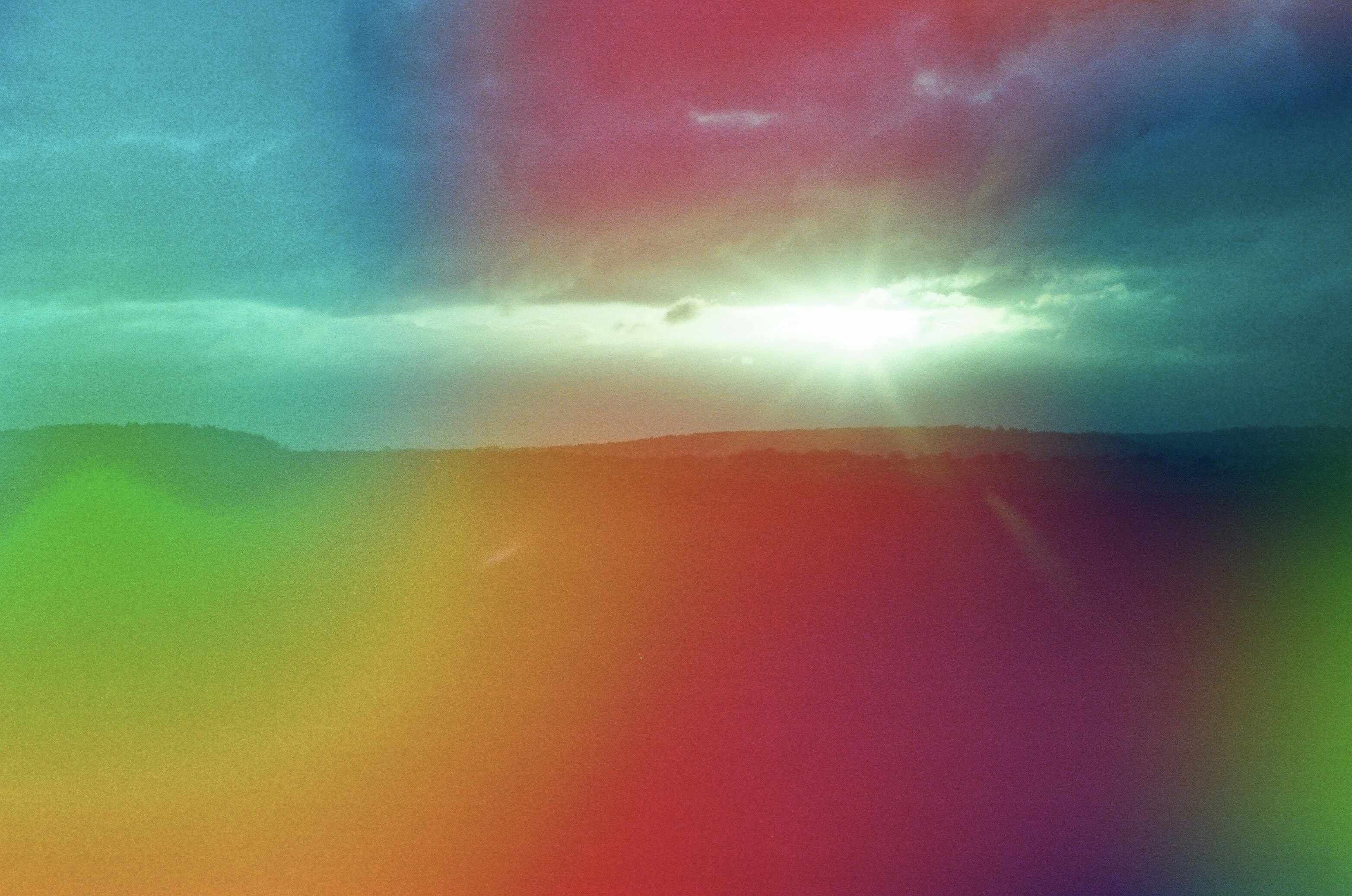 Sunlight breaking through clouds over colorful landscape.