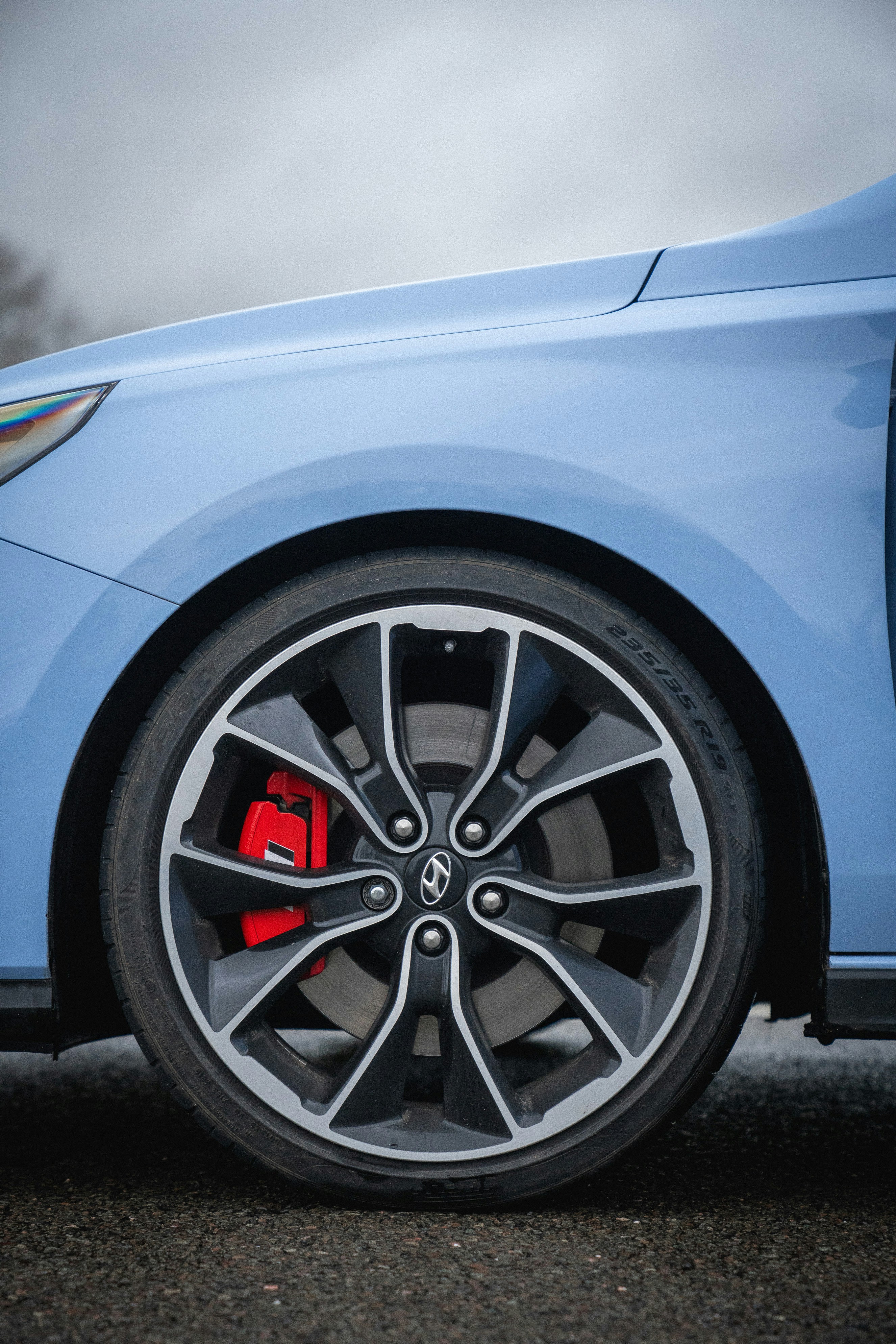 Close-up of a blue car wheel with red brake caliper.