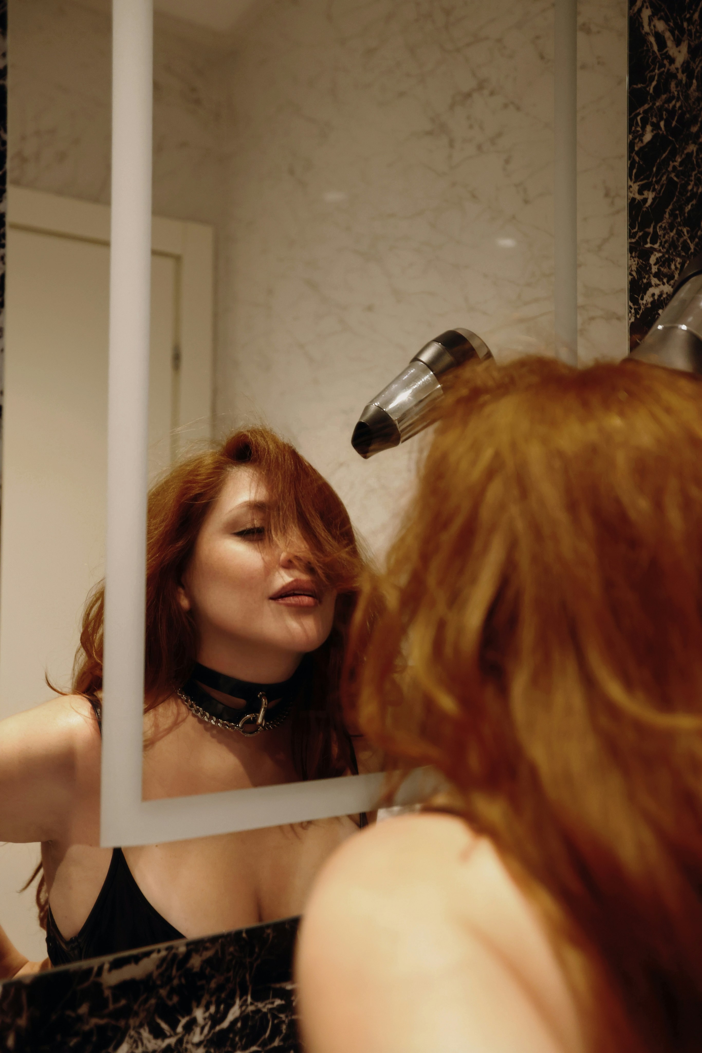 Frau mit roten Haaren trocknet sich im Spiegel die Haare