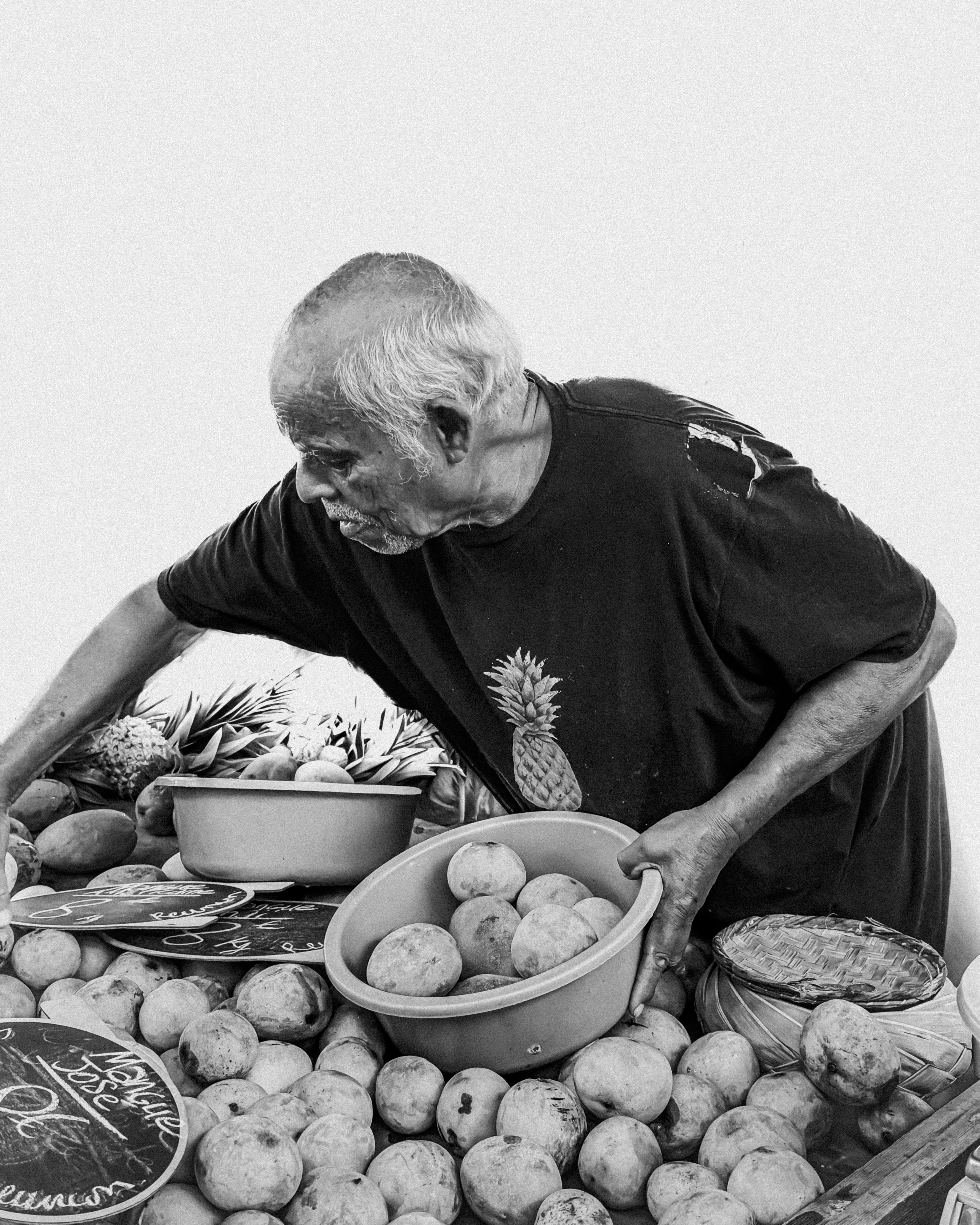Elderly man arranging fruit at a market stall