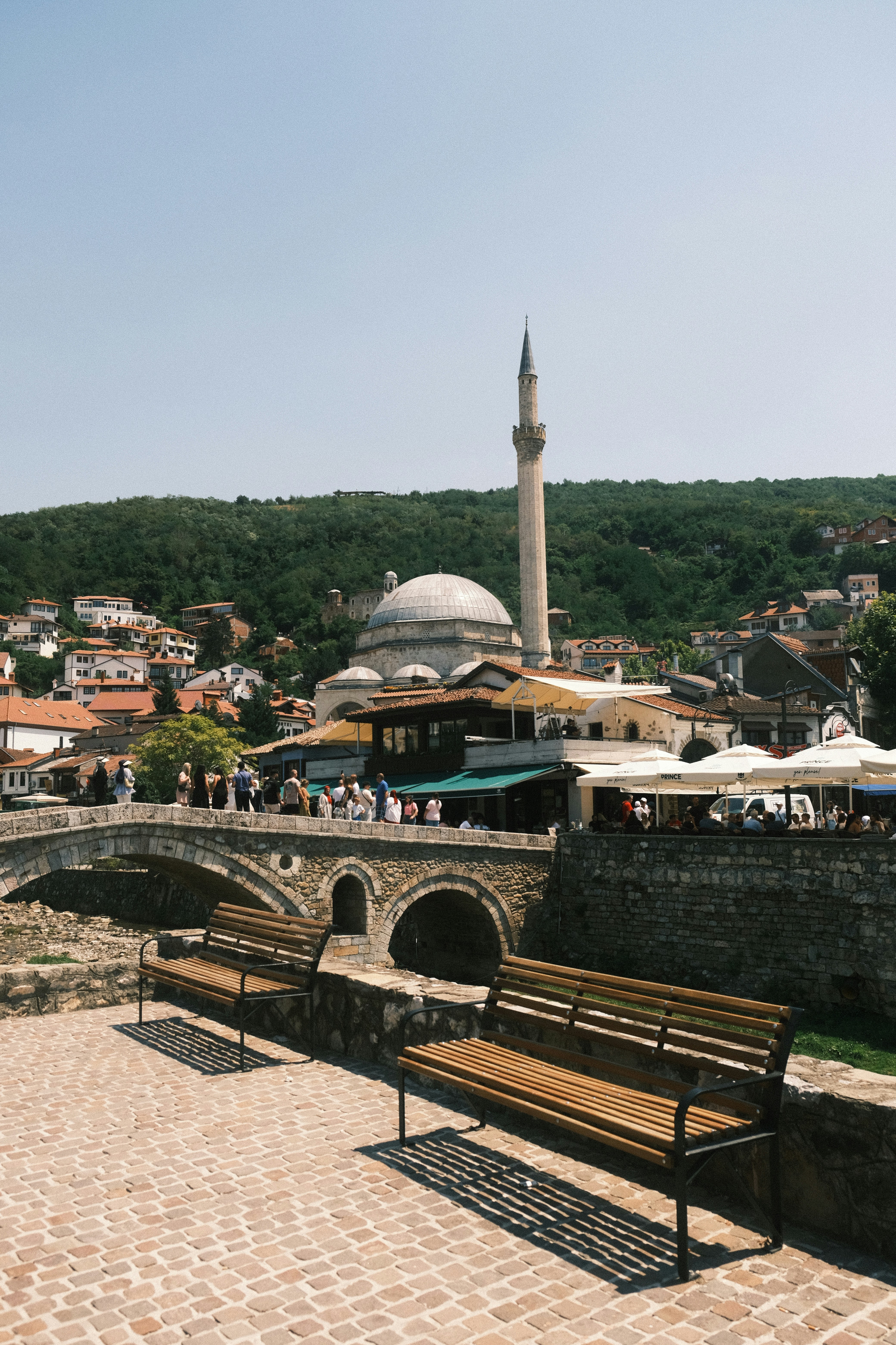 Stone bridge with mosque and bustling outdoor cafe