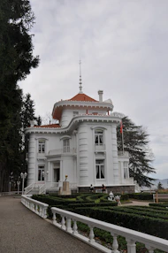 White mansion with red roof surrounded by manicured gardens