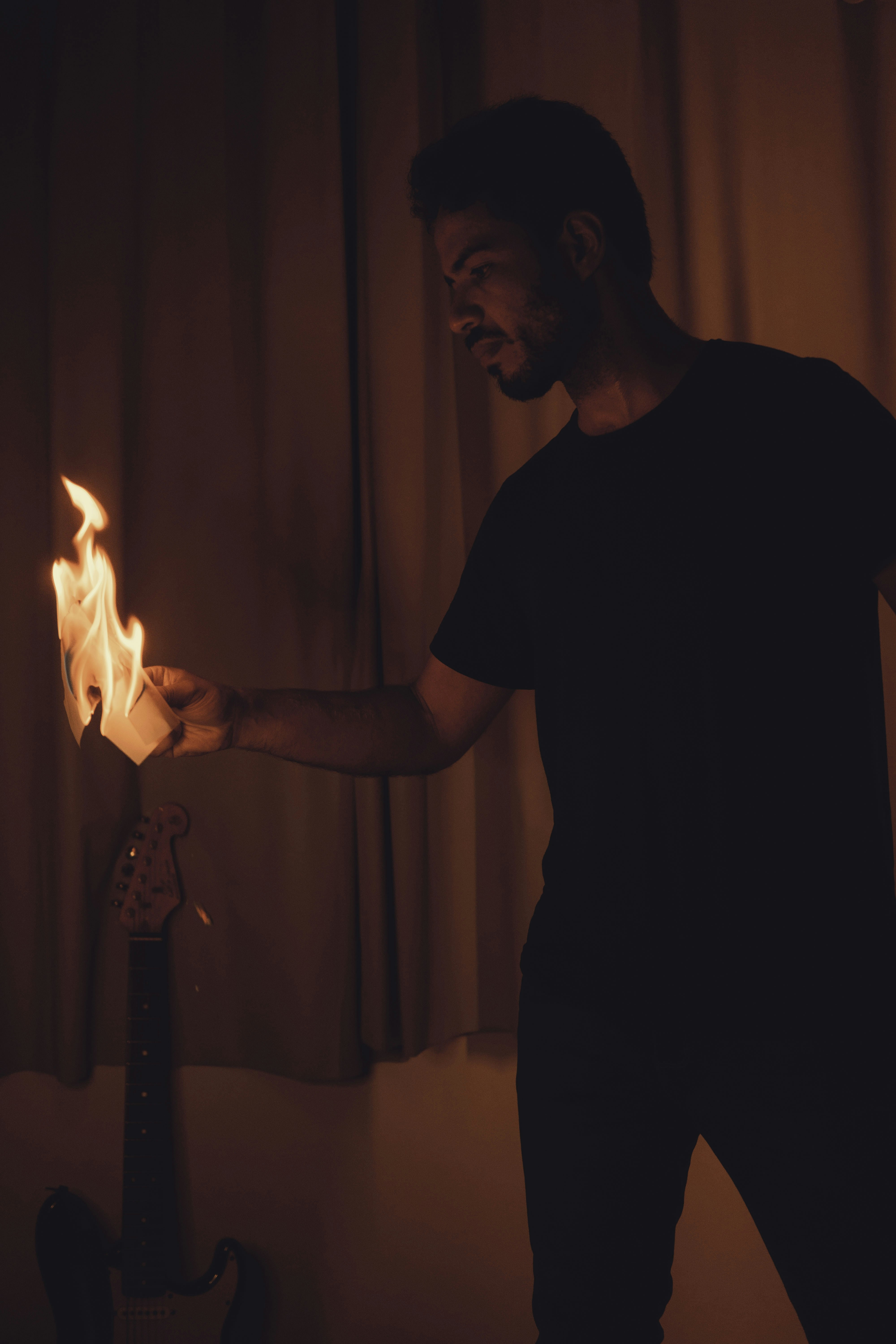 Man holding burning object near guitar