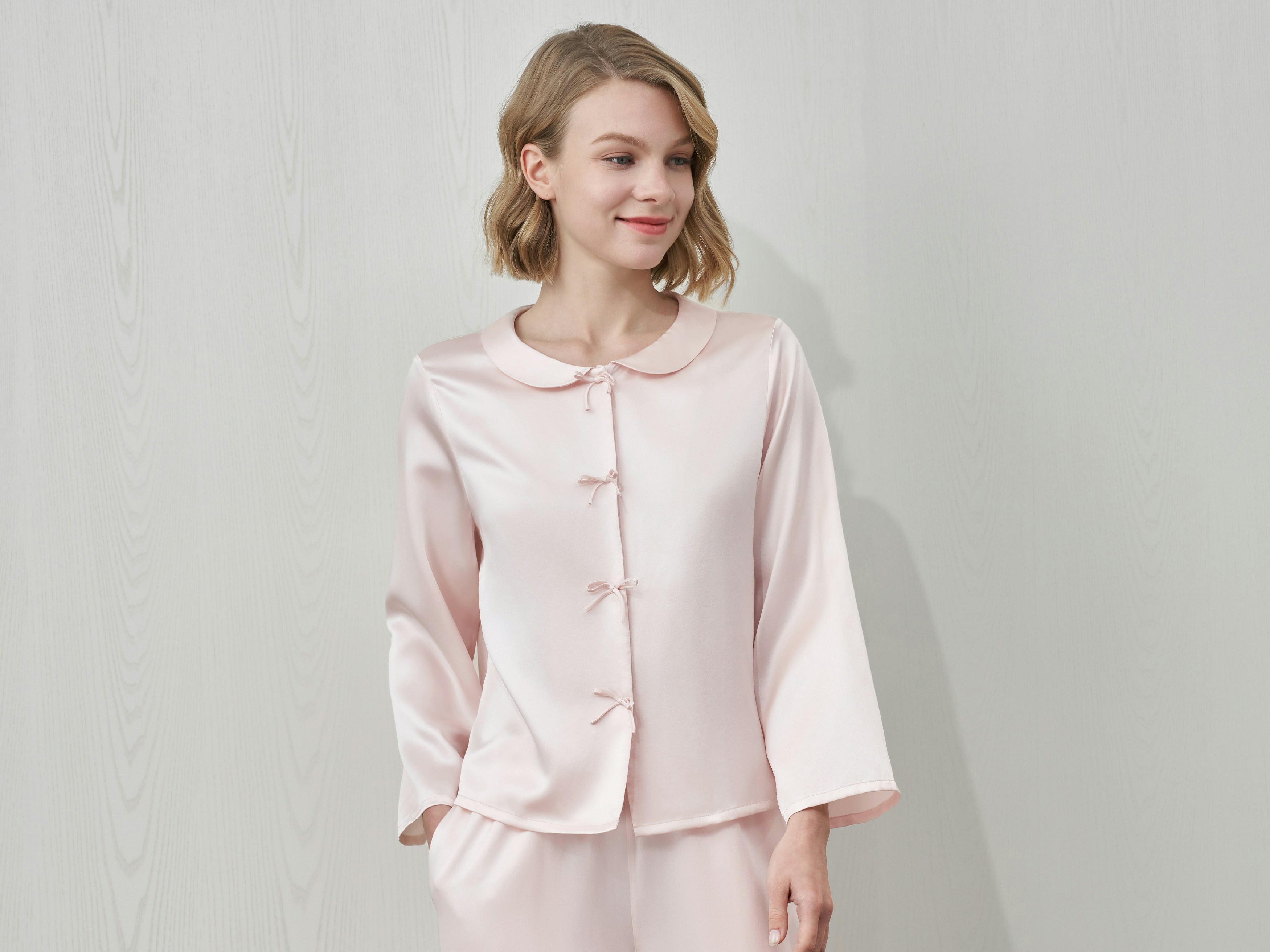 A woman in a pink silk pajama set