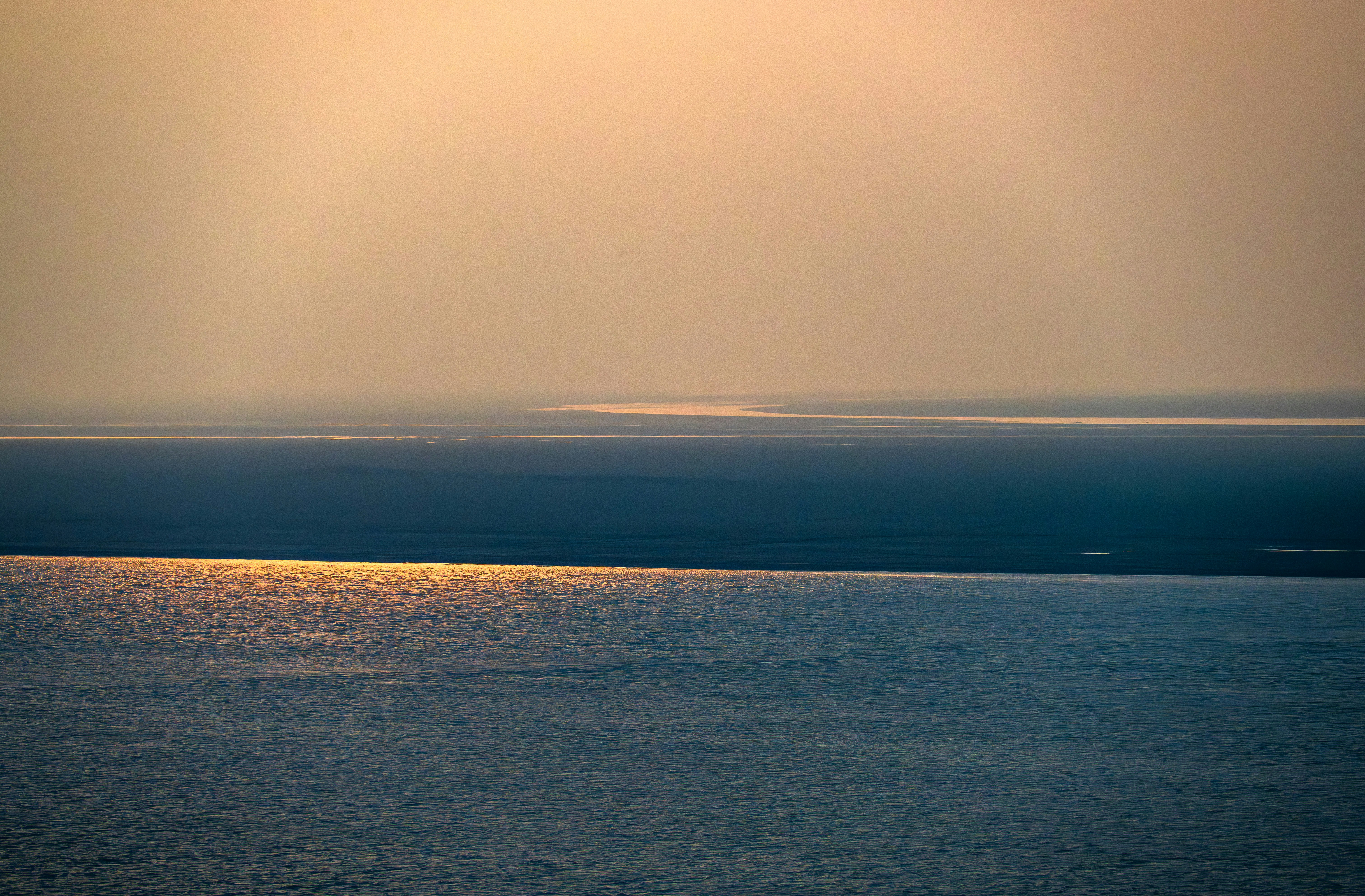 黄金色の夕焼けの光が穏やかな海面に反射している