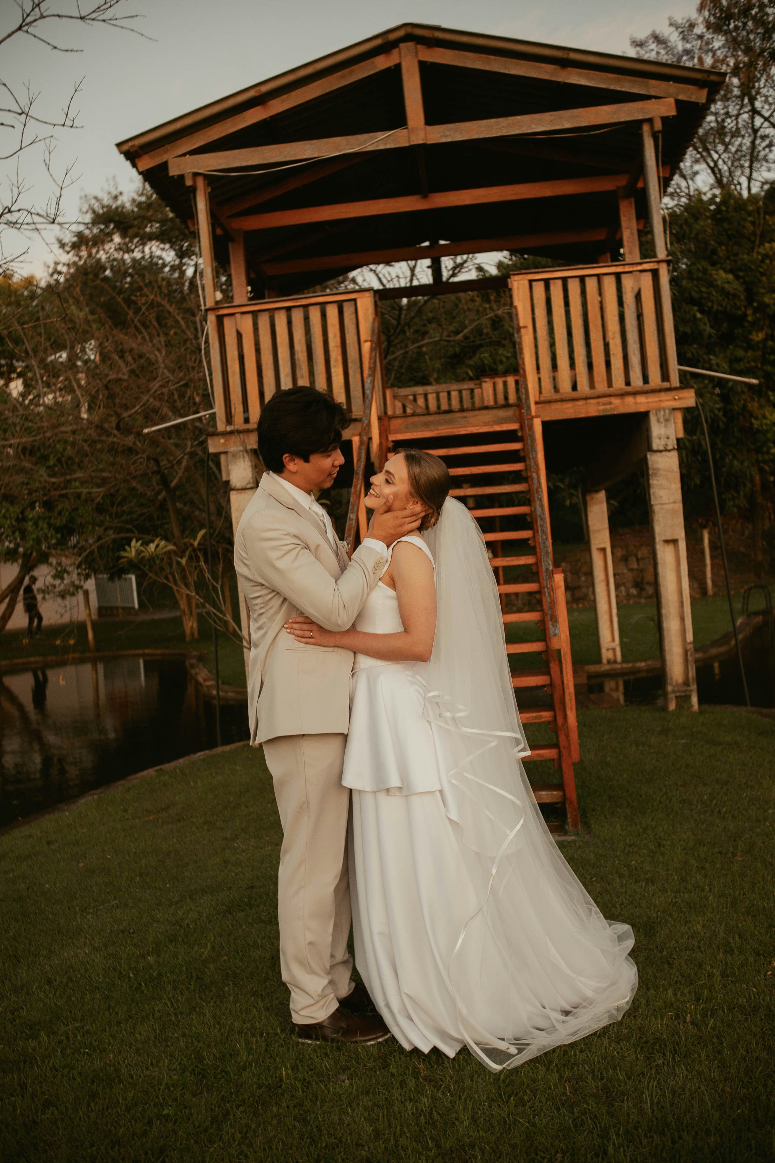 Die Frischvermählten umarmen sich bei Einbruch der Dämmerung in der Nähe eines Holzgebäudes