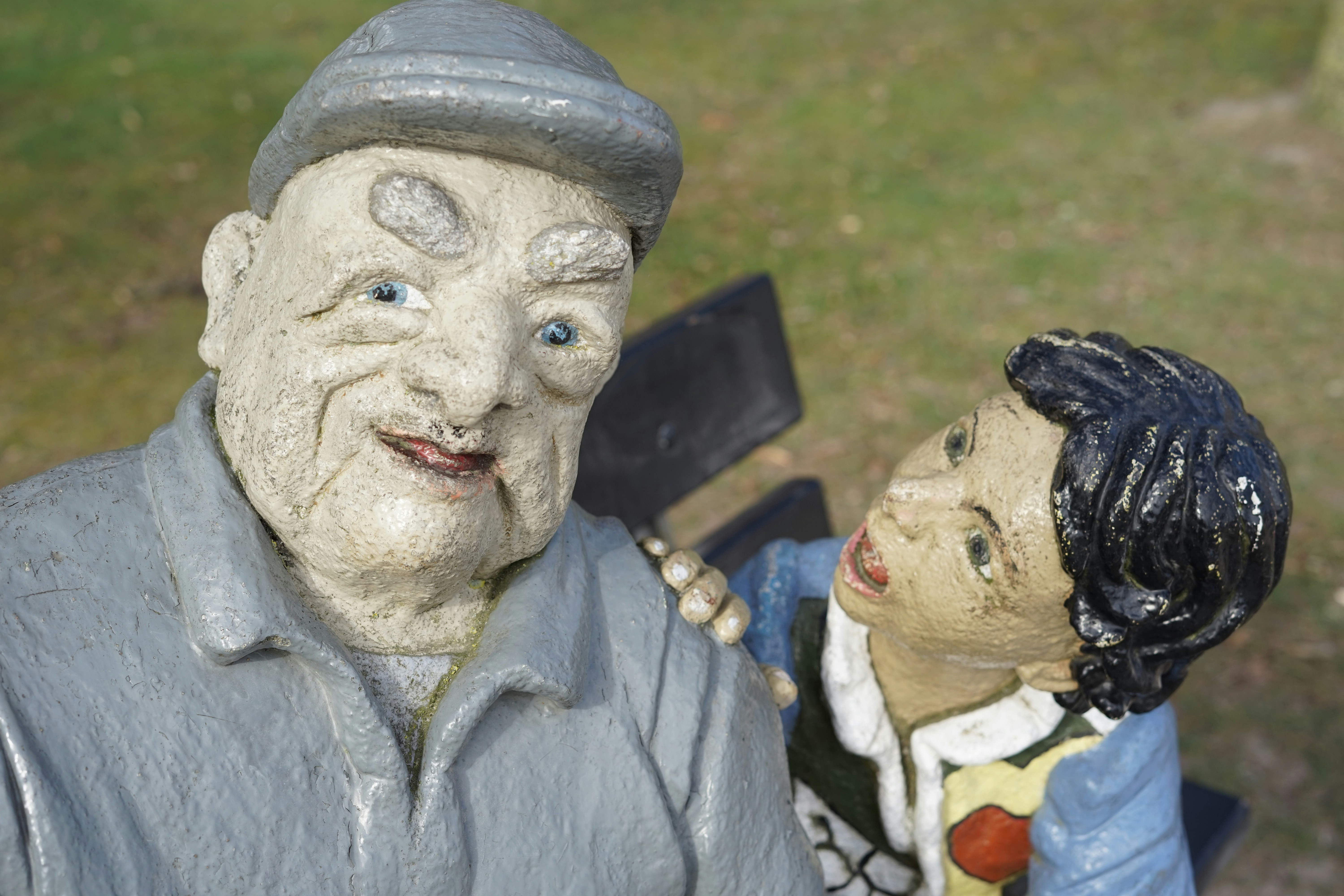 Duas estátuas desgastadas de um velho e uma criança.