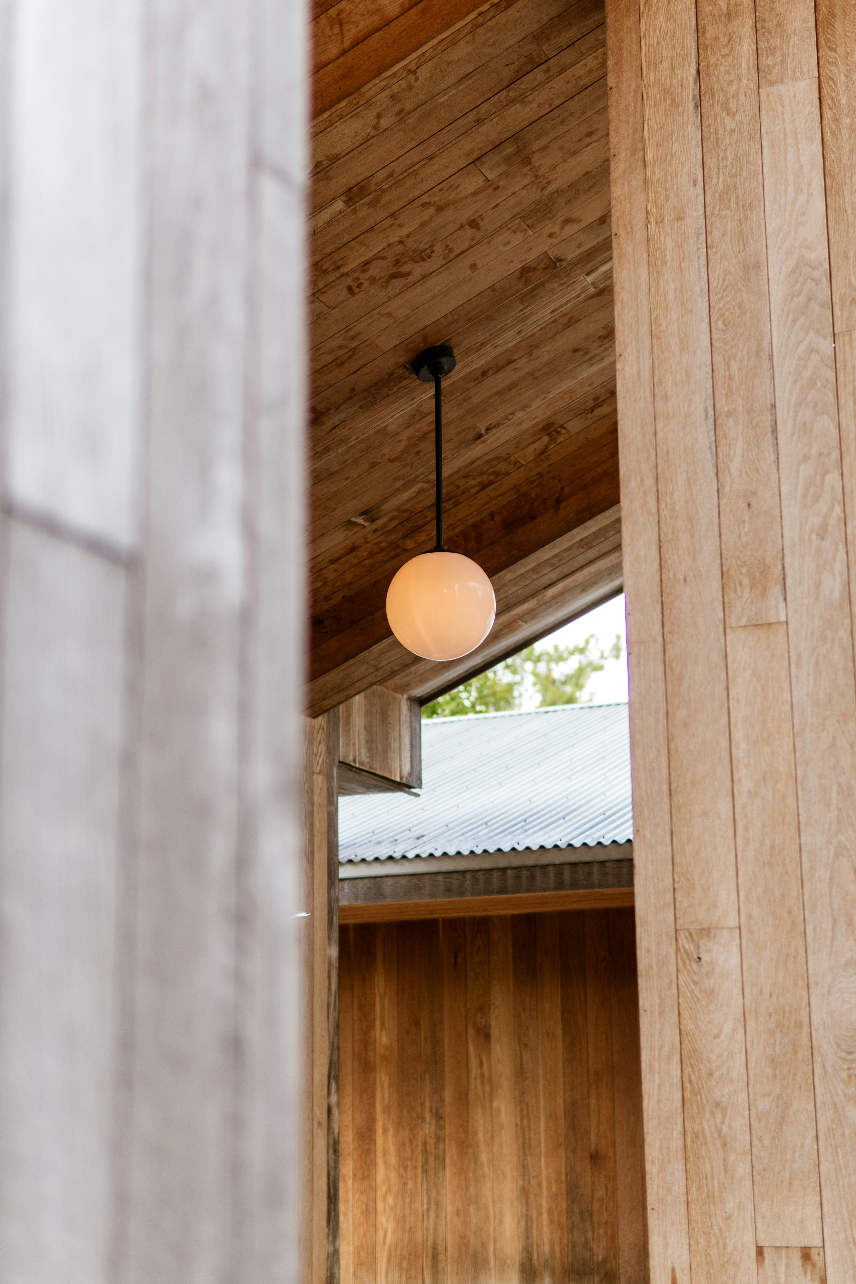 A spherical lamp hangs from a wooden ceiling.