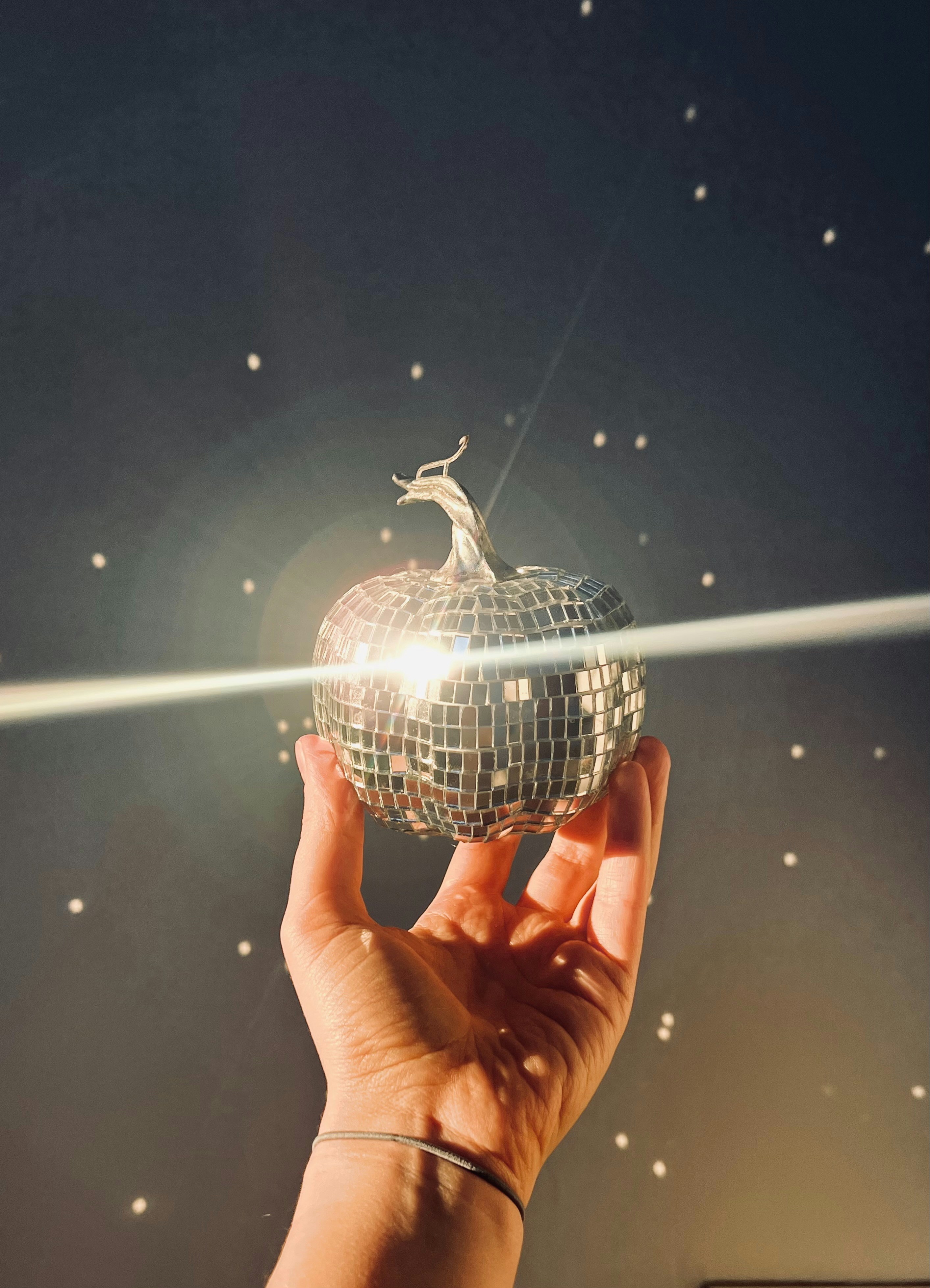 Hand holding a disco ball shaped pumpkin
