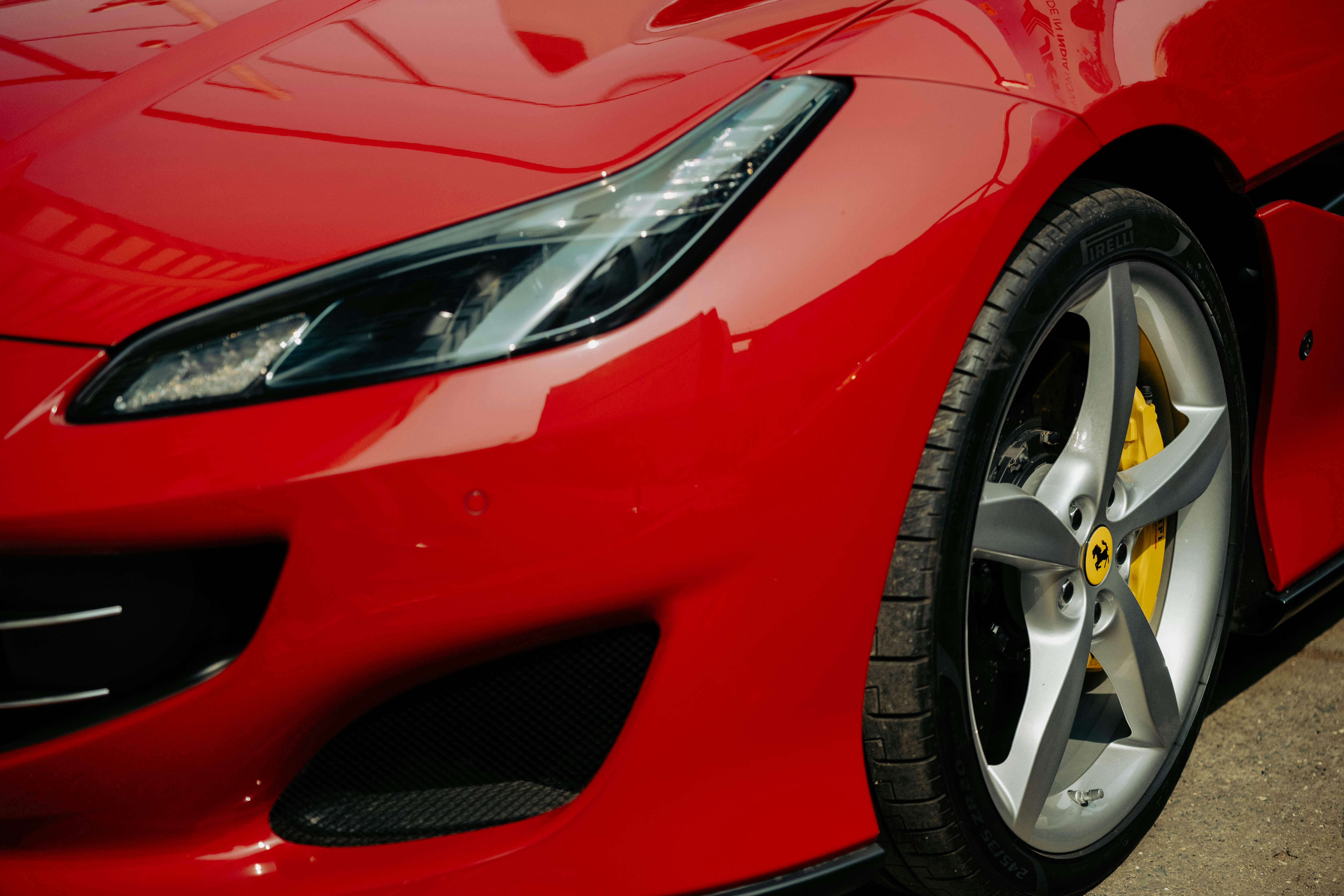 Close-up of a shiny red sports car headlight and wheel.